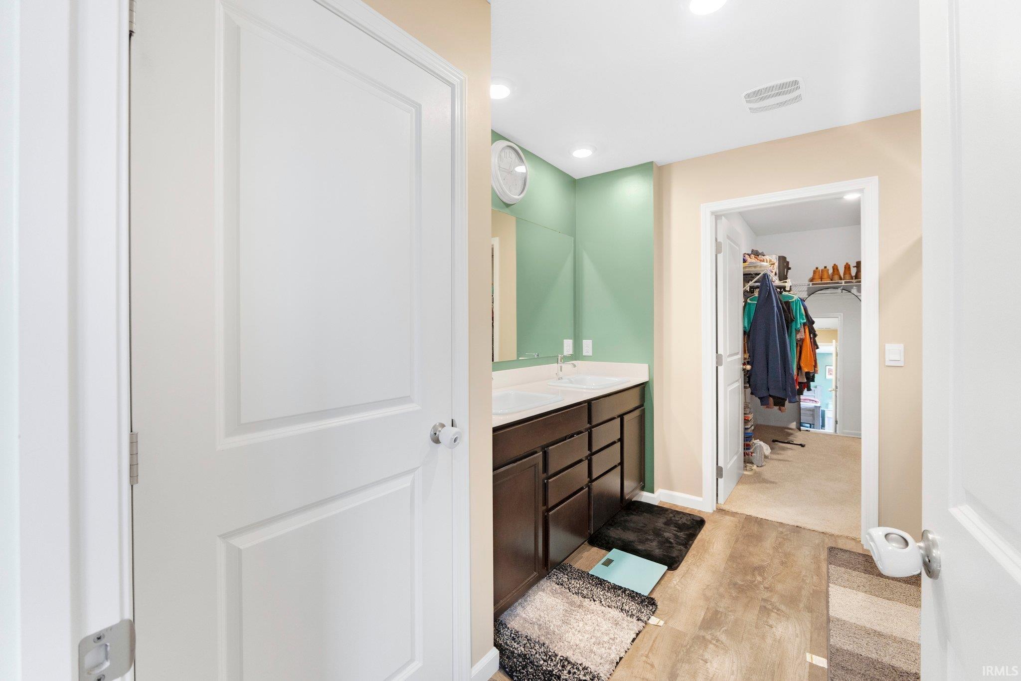 Bathroom vanity with dual sinks, dark wood cabinetry, and a full-width mirror