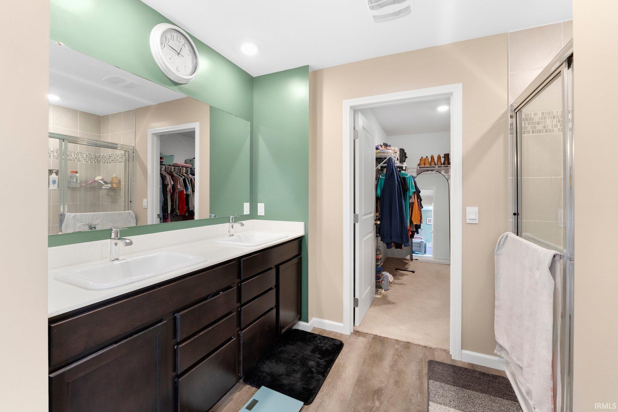 Bathroom featuring a double vanity with white countertops, dark wood cabinetry, and a large mirror
