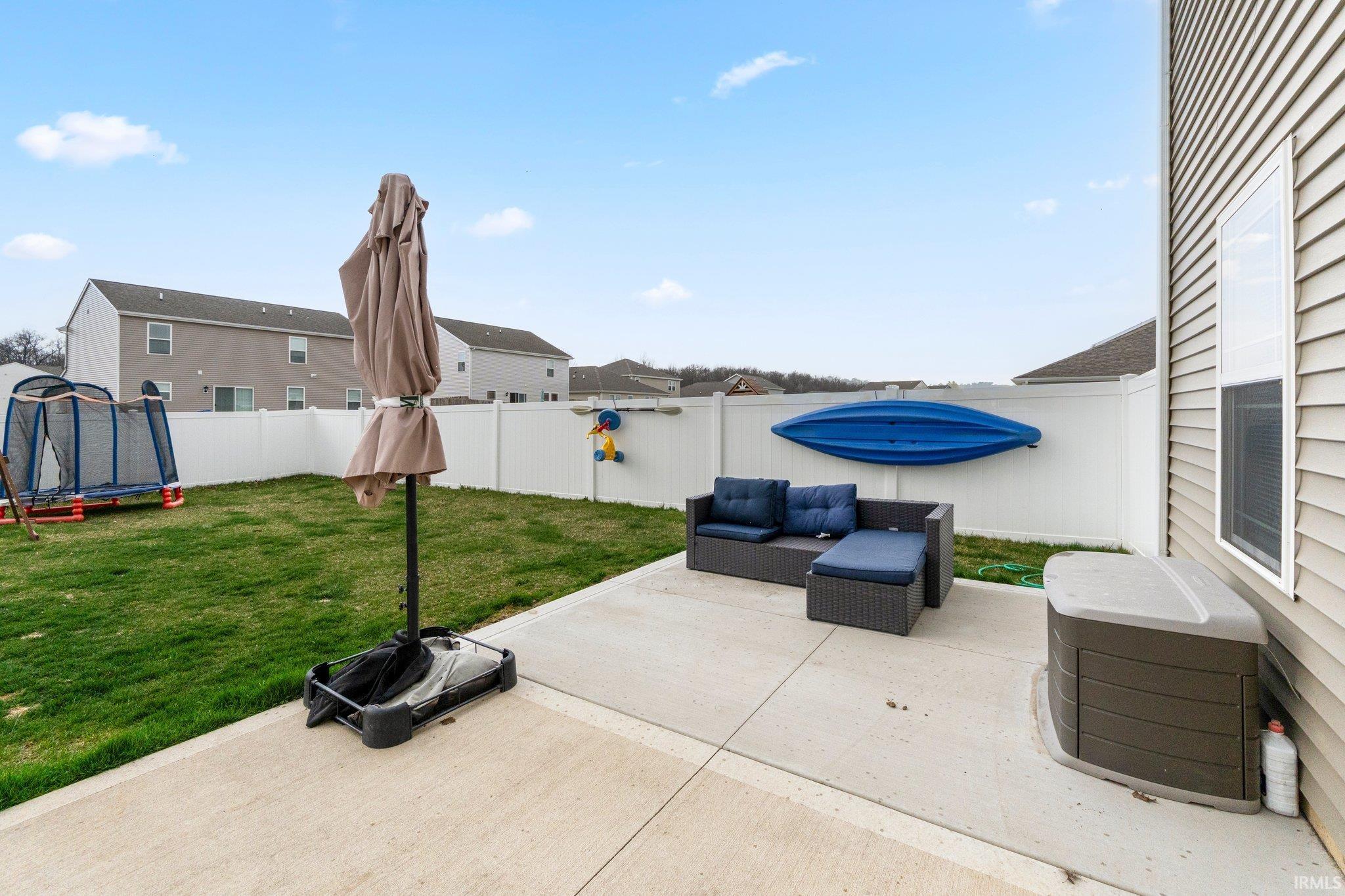 Concrete patio area with a white privacy fence and green lawn