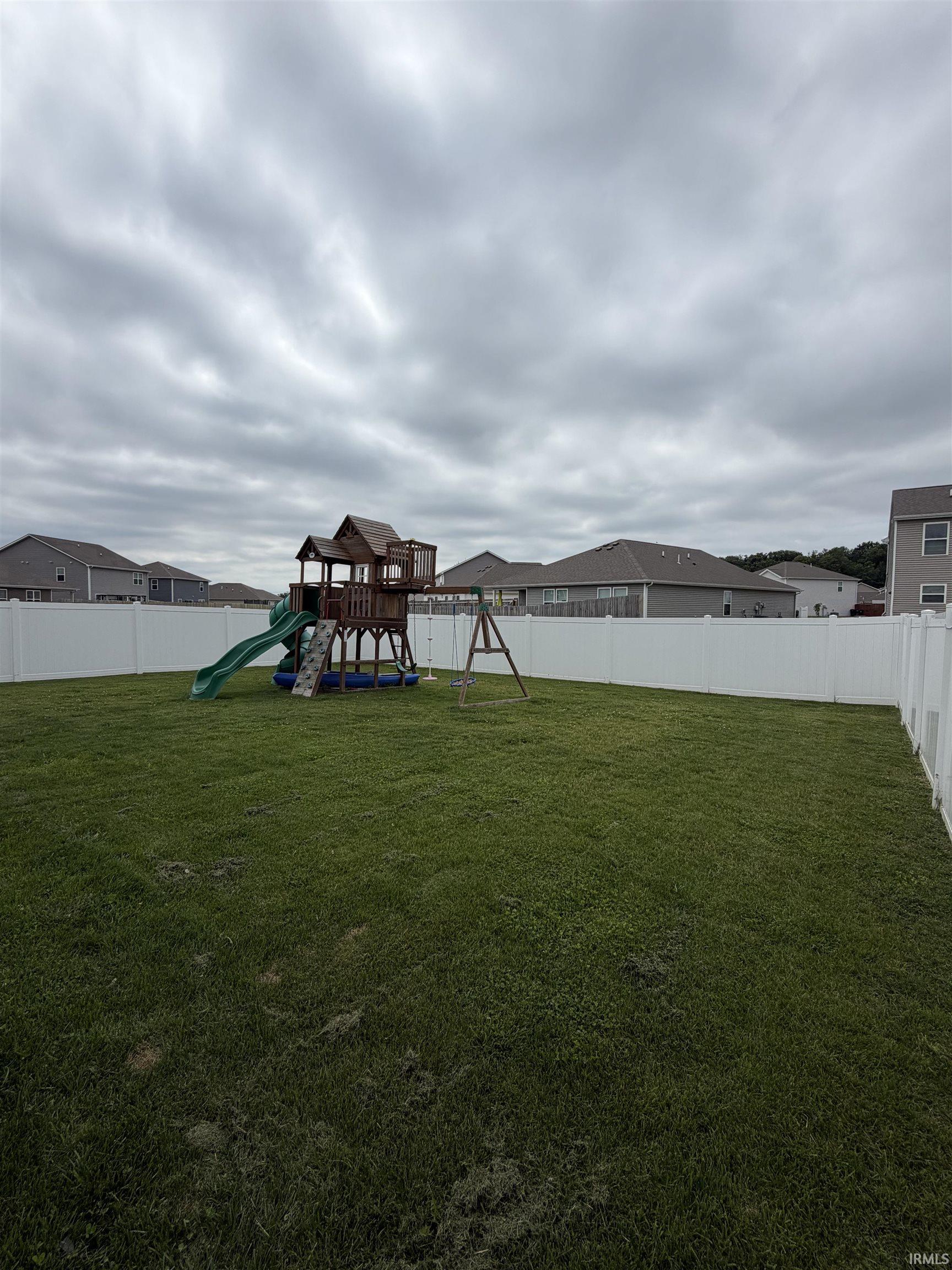 Expansive green lawn enclosed by a white privacy fence
