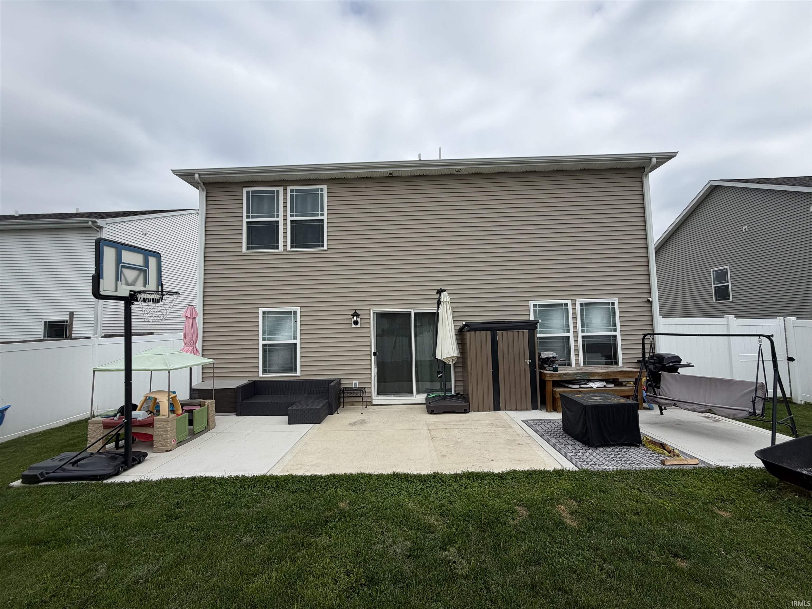 Rear exterior featuring tan horizontal siding and multiple windows