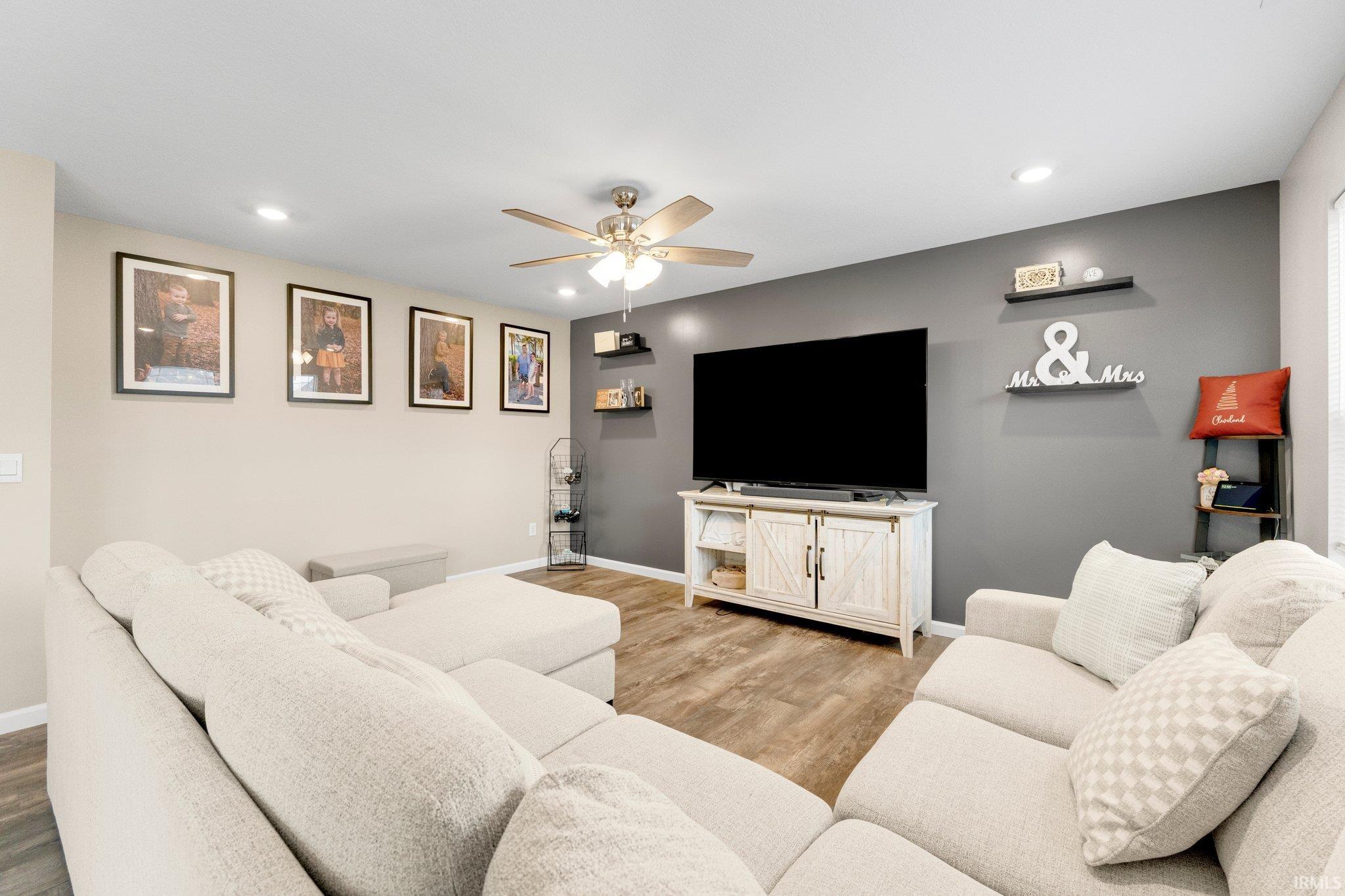 Living area featuring wood-finish flooring, a ceiling fan with integrated lighting, and recessed ceiling lights