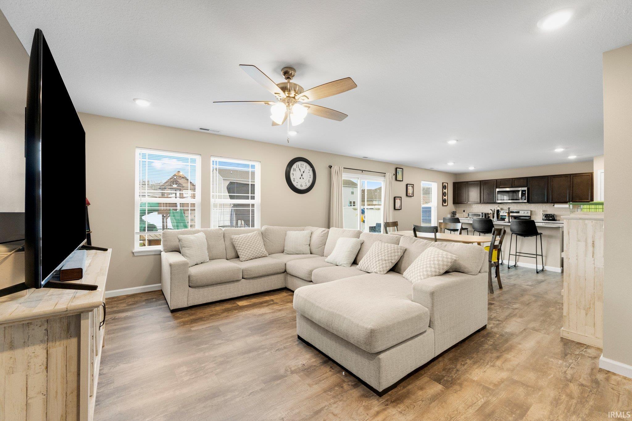 Open-concept living area with wood-finish flooring, recessed lighting, and a ceiling fan