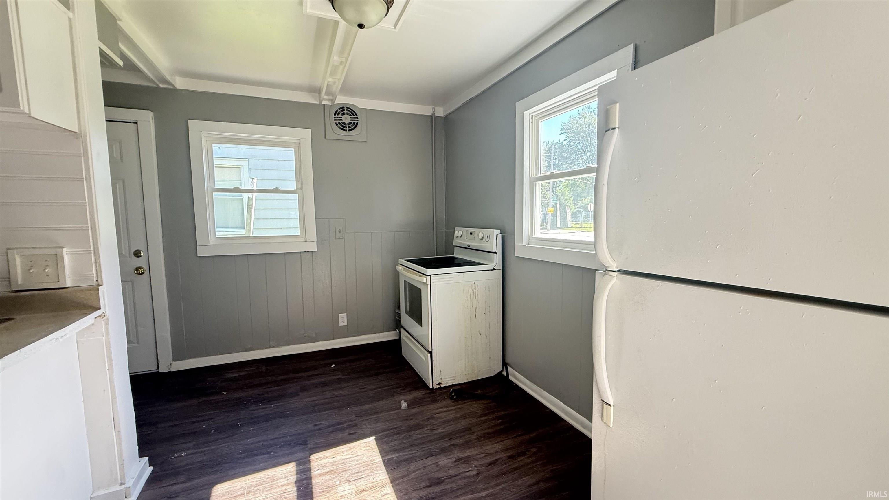 Kitchen space featuring wood-finish flooring, white appliances, and painted paneling
