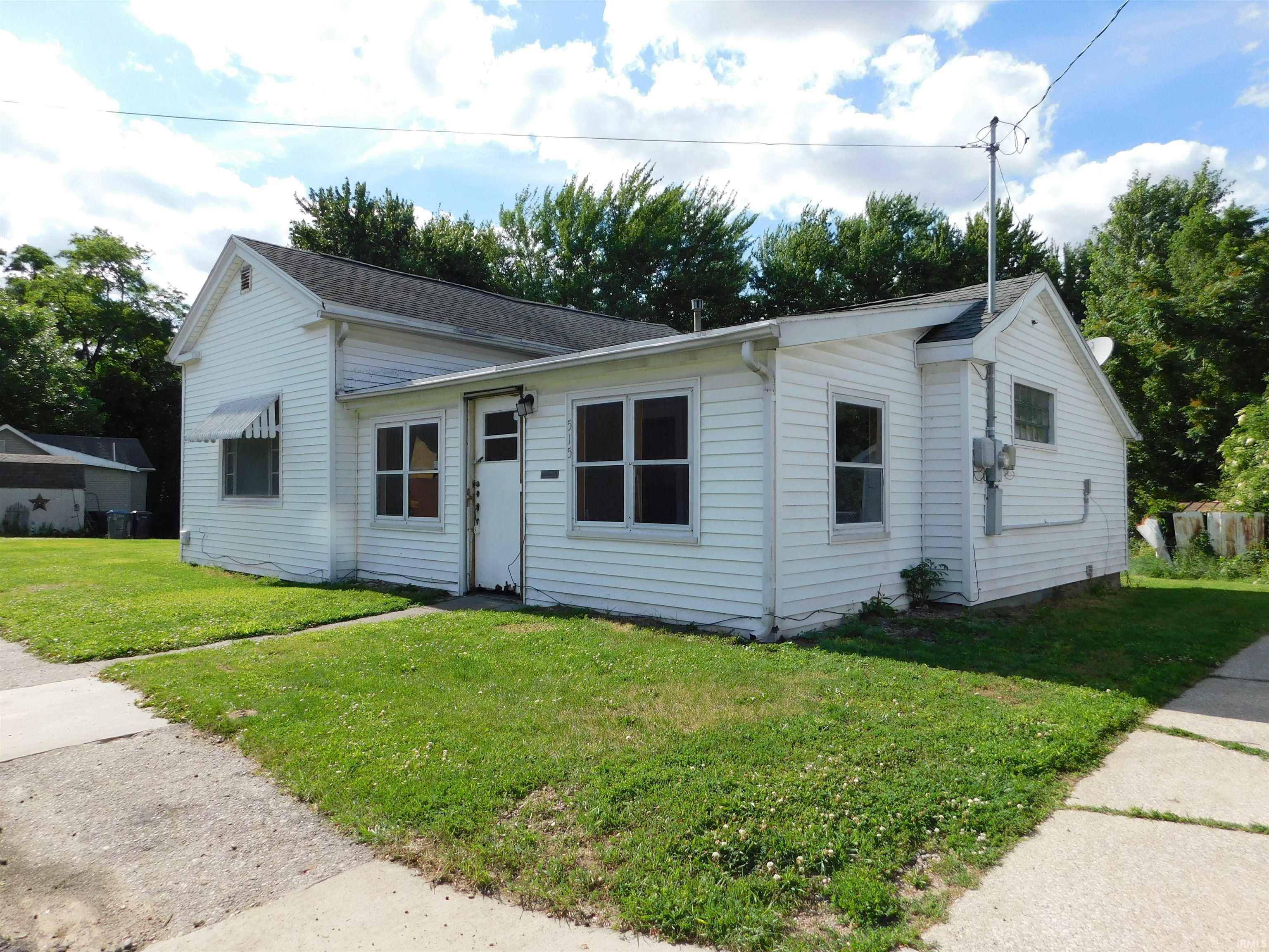 White siding exterior with a dark shingle roof and a front lawn