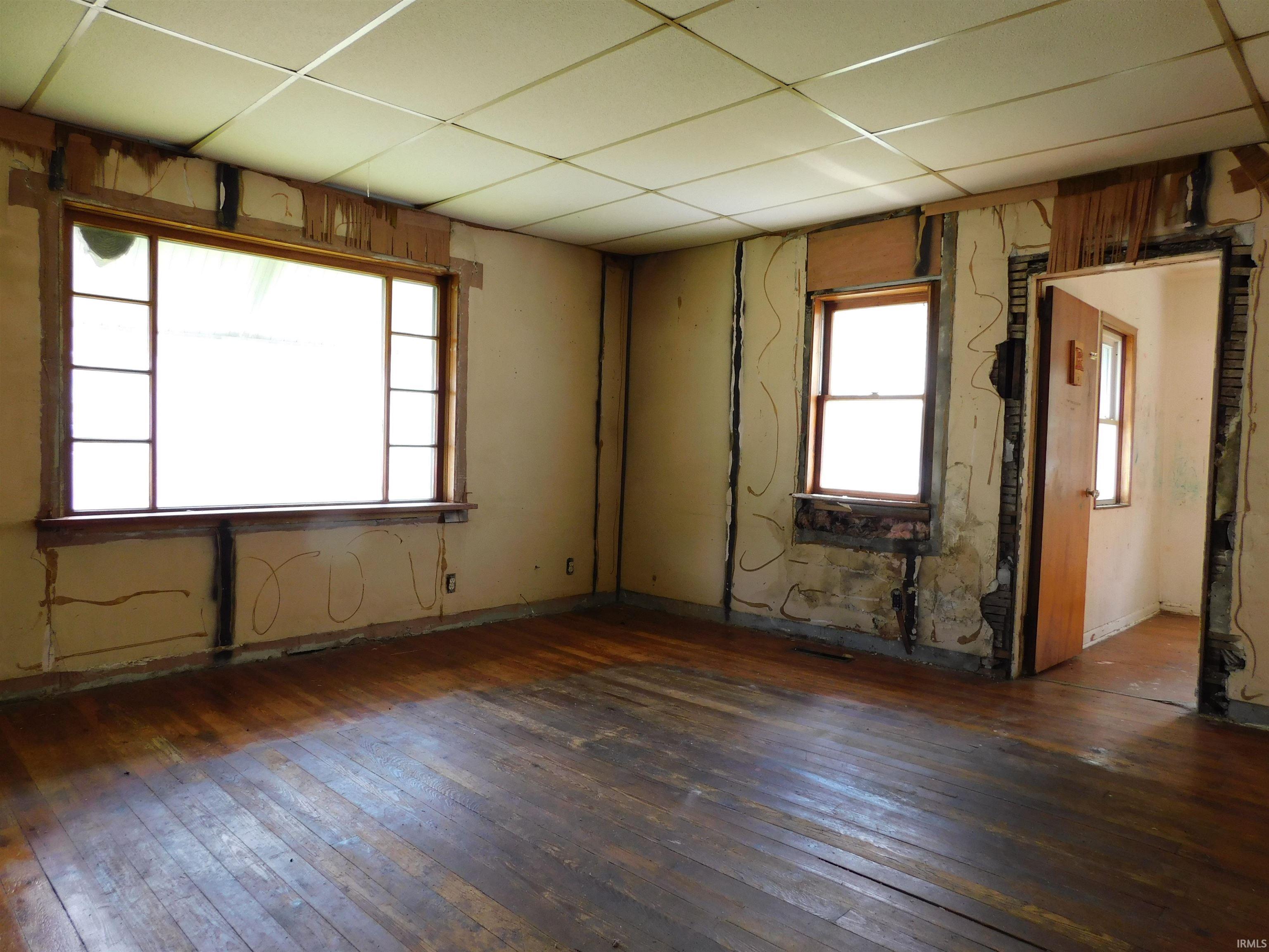 Interior space featuring wood-finish flooring, multiple windows with natural wood frames, and a drop ceiling