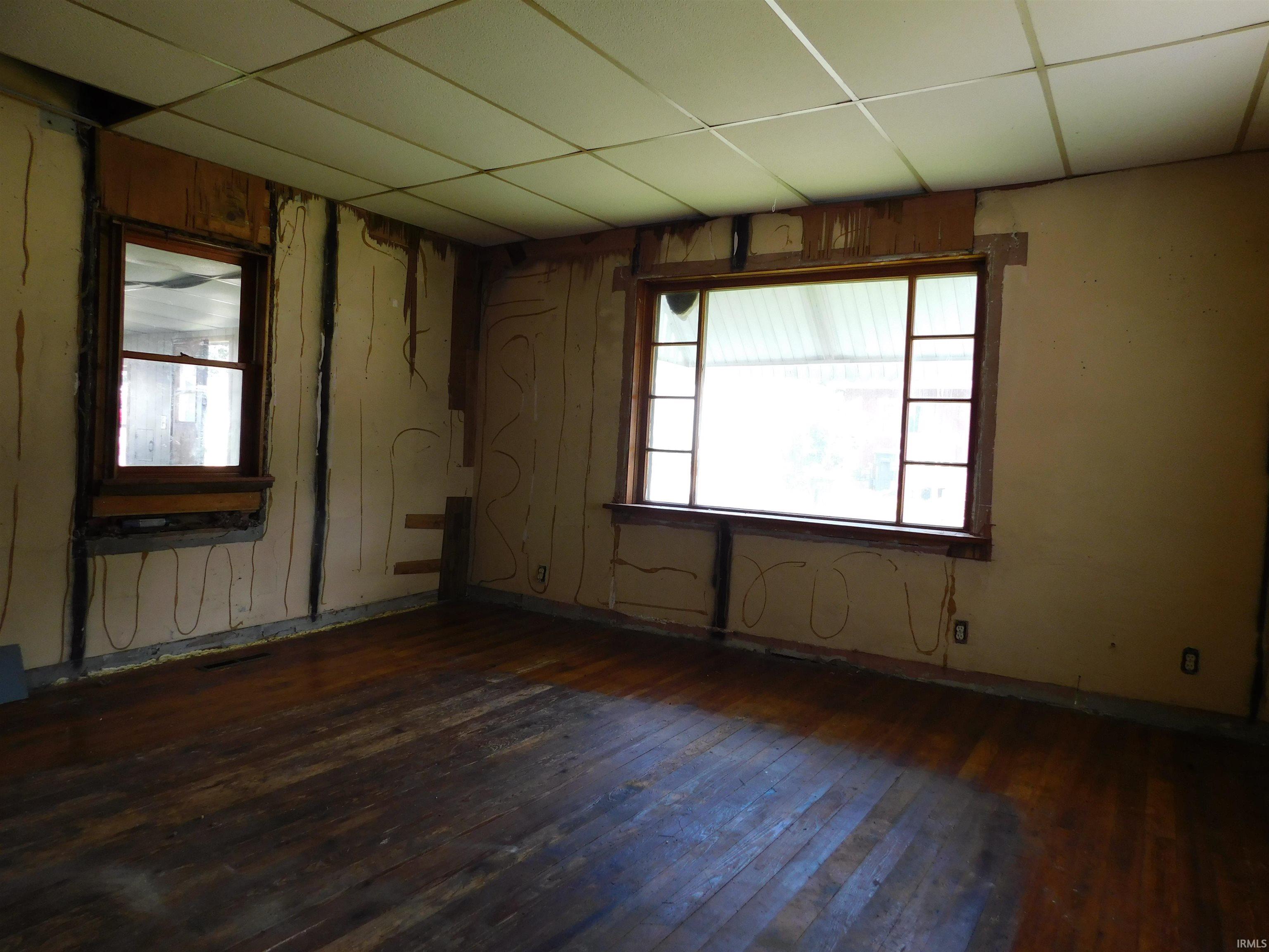 Room featuring multiple windows, exposed wall studs, and wood-finish flooring