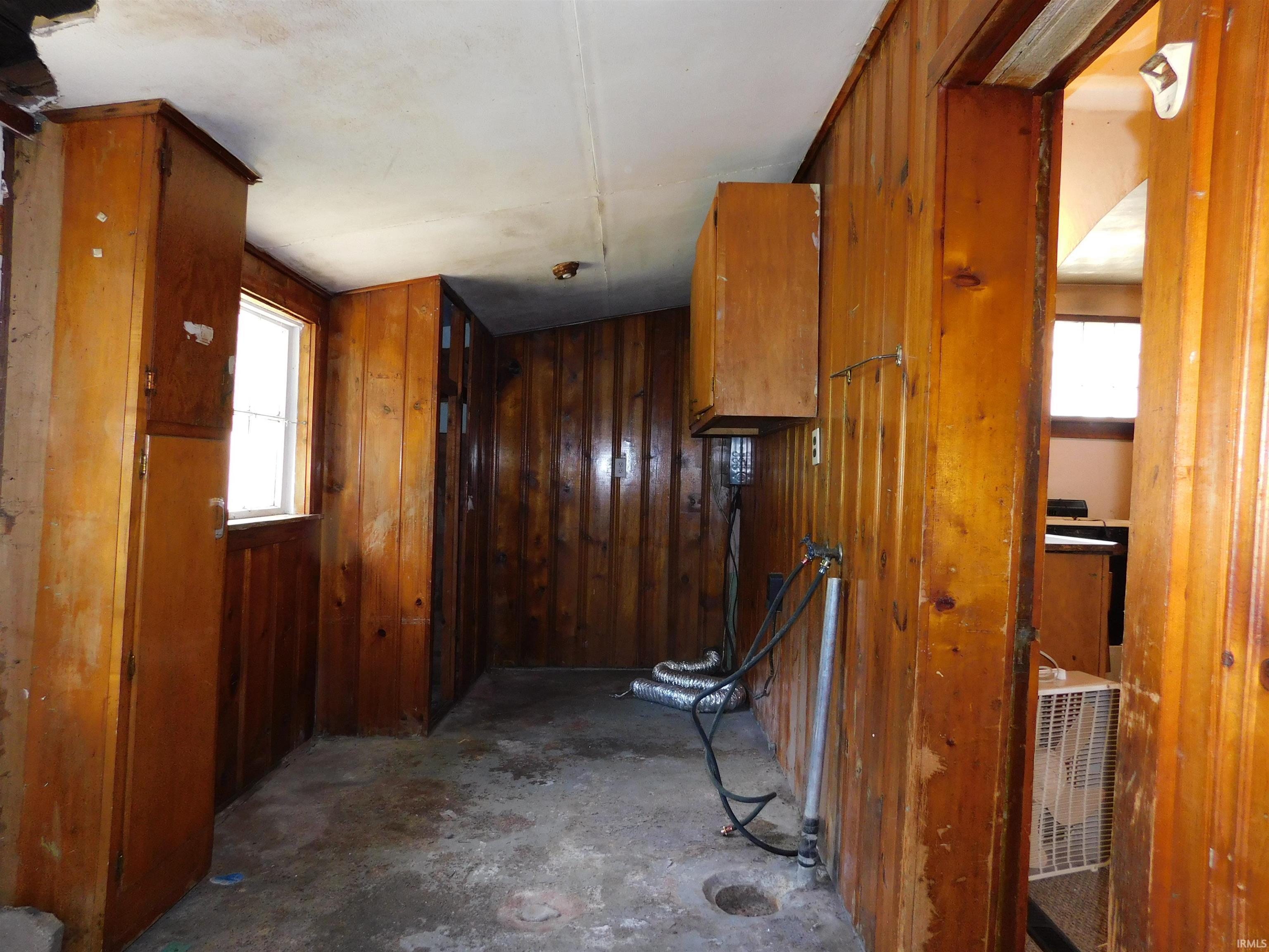 Room featuring wood-paneled walls, built-in cabinetry, and a window providing natural light