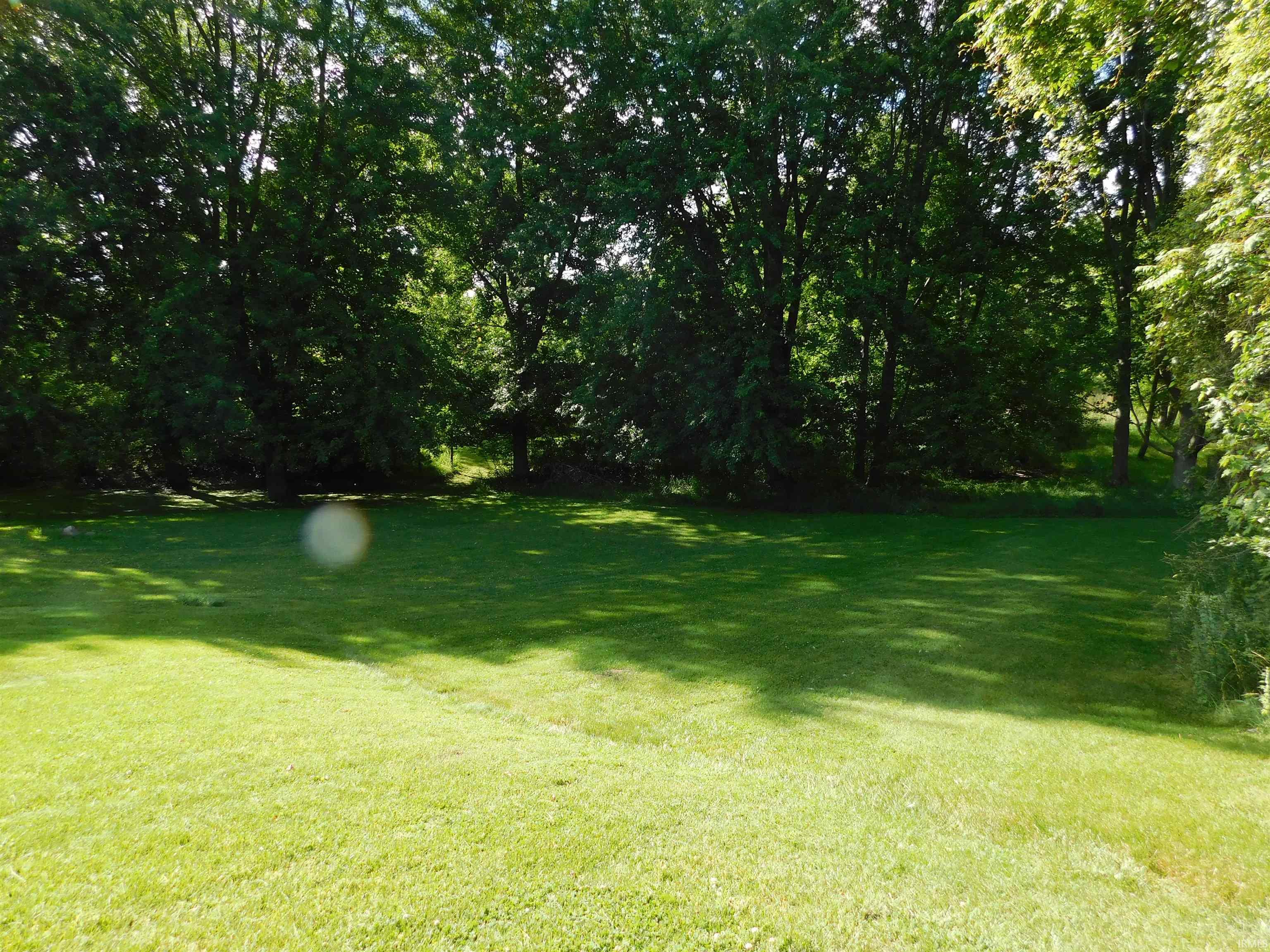 Expansive green lawn with mature trees providing a natural perimeter