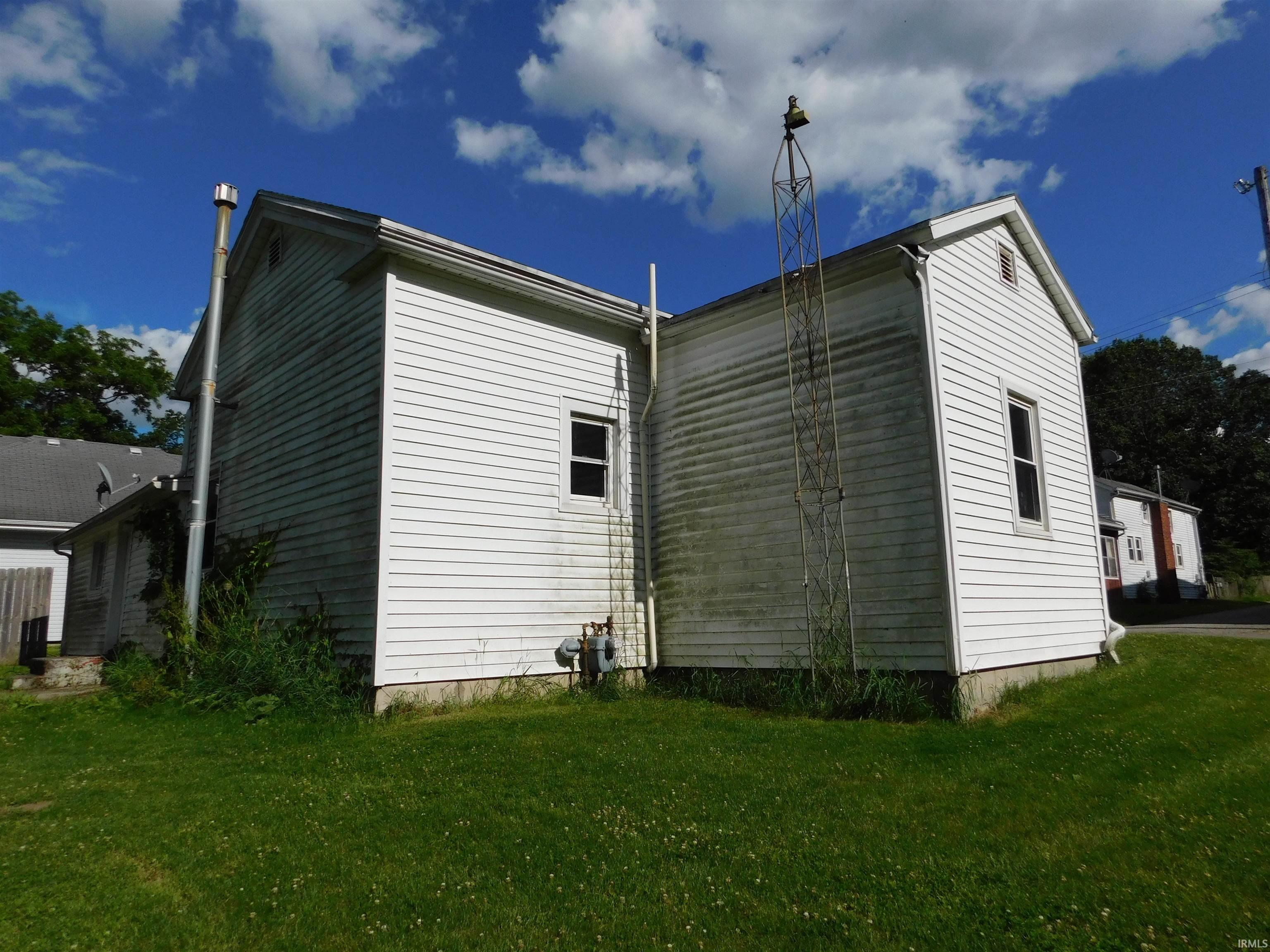 White siding exterior with multiple windows, a foundation perimeter, and a pitched roofline