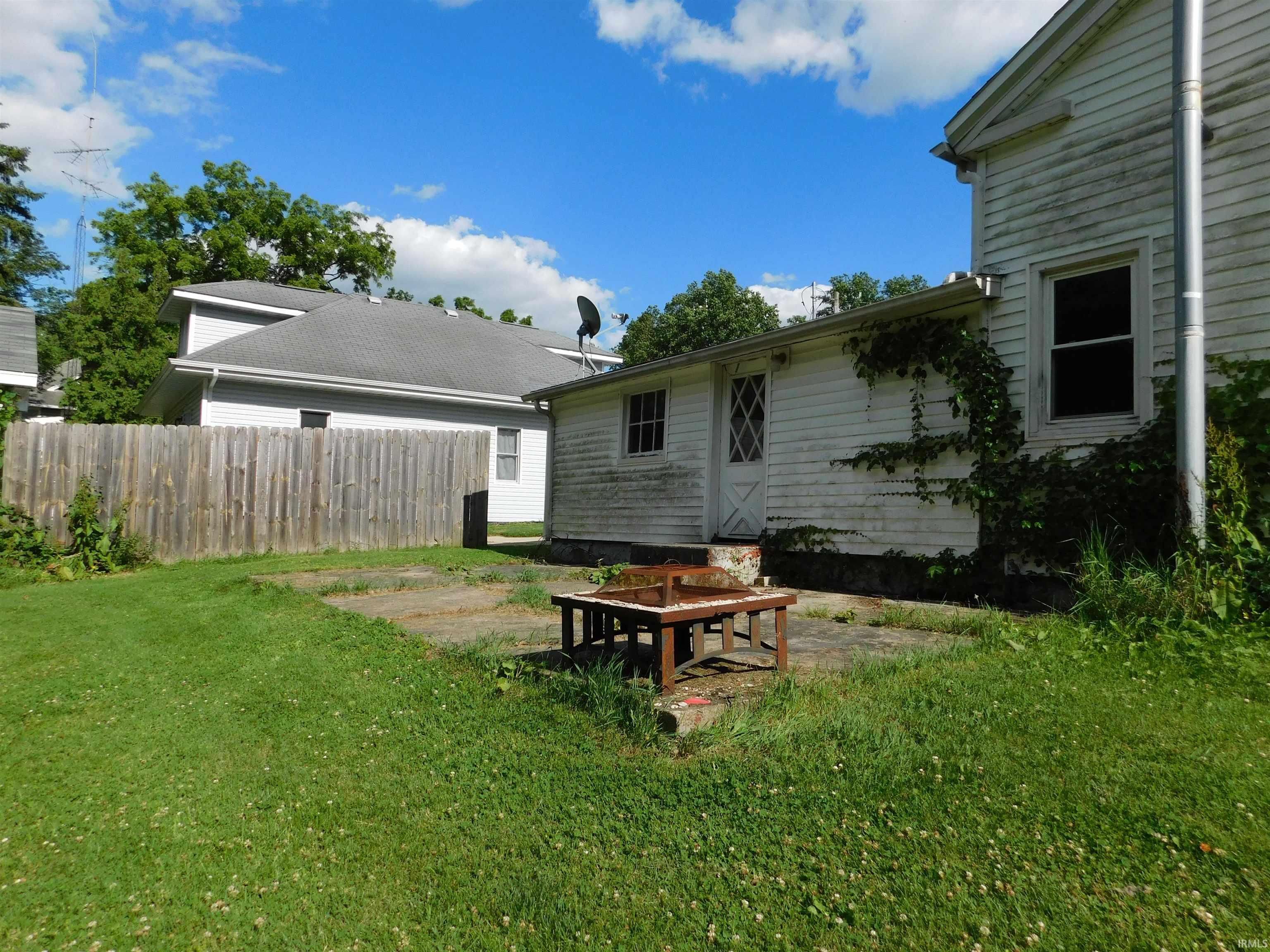 Rear exterior featuring white siding, a single window, and a door with diamond-patterned lites