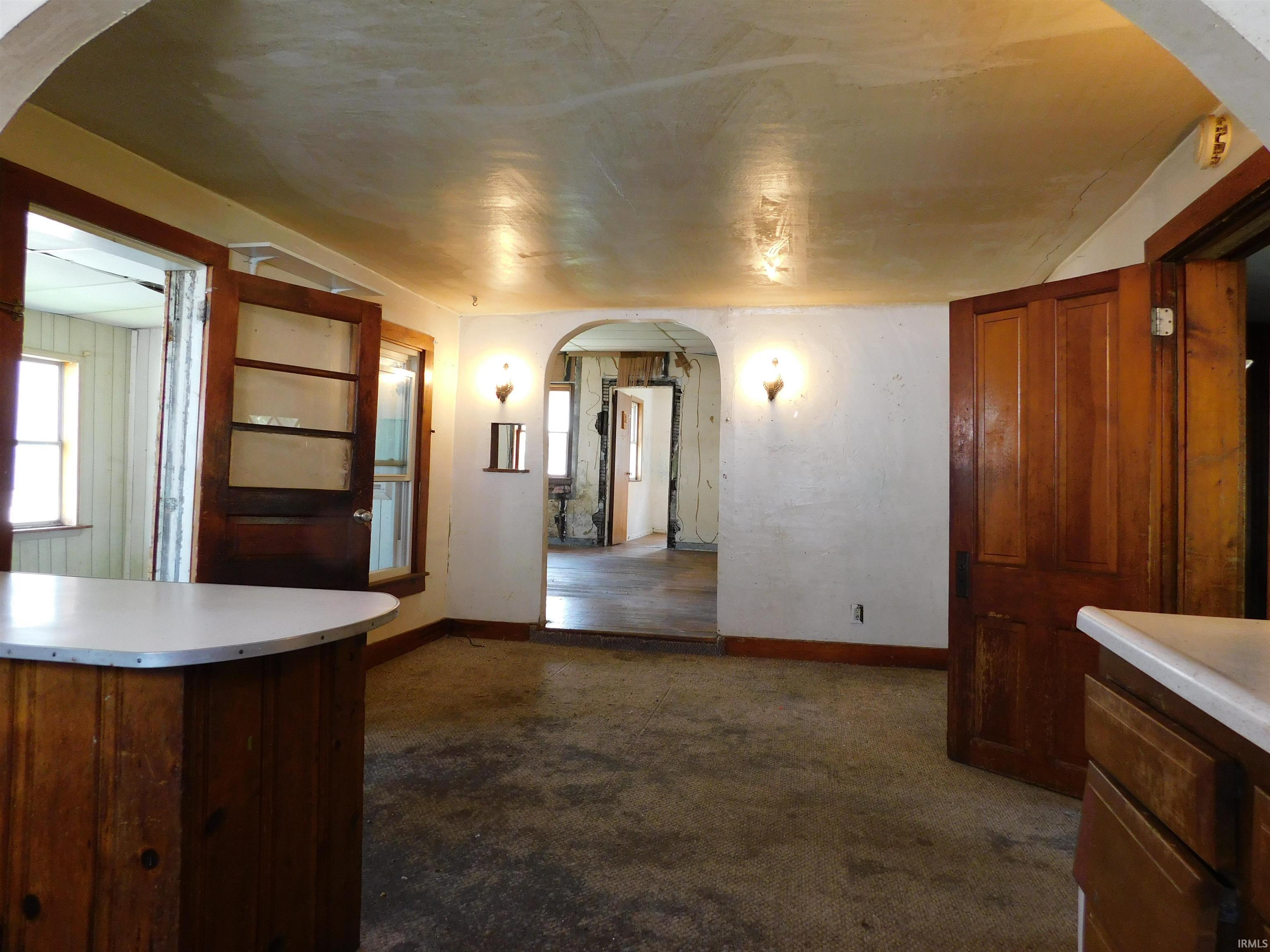 Interior space featuring an arched doorway, wood paneling, and wall sconces