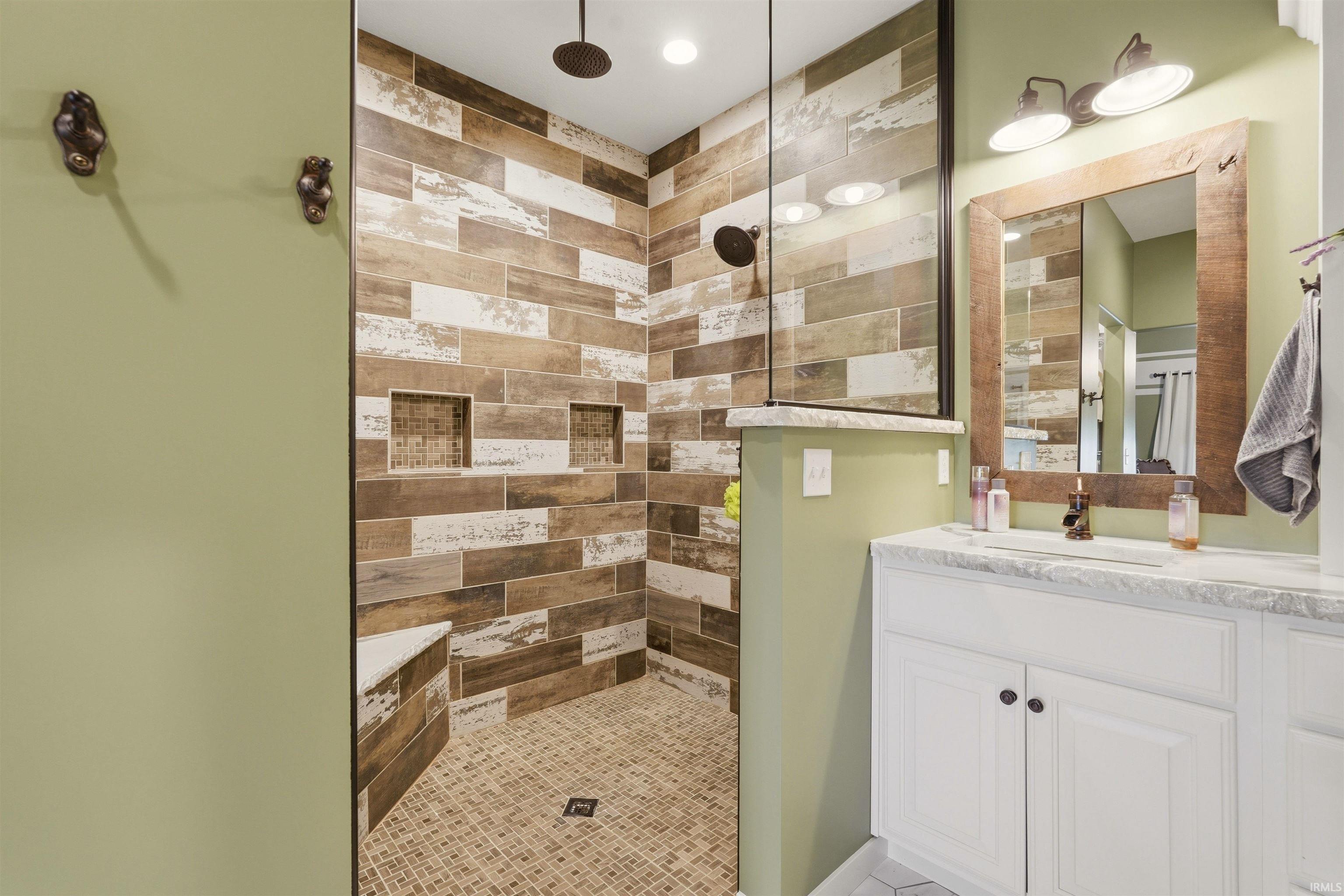 Walk-in shower featuring wood-look tile, built-in niches, and a corner bench