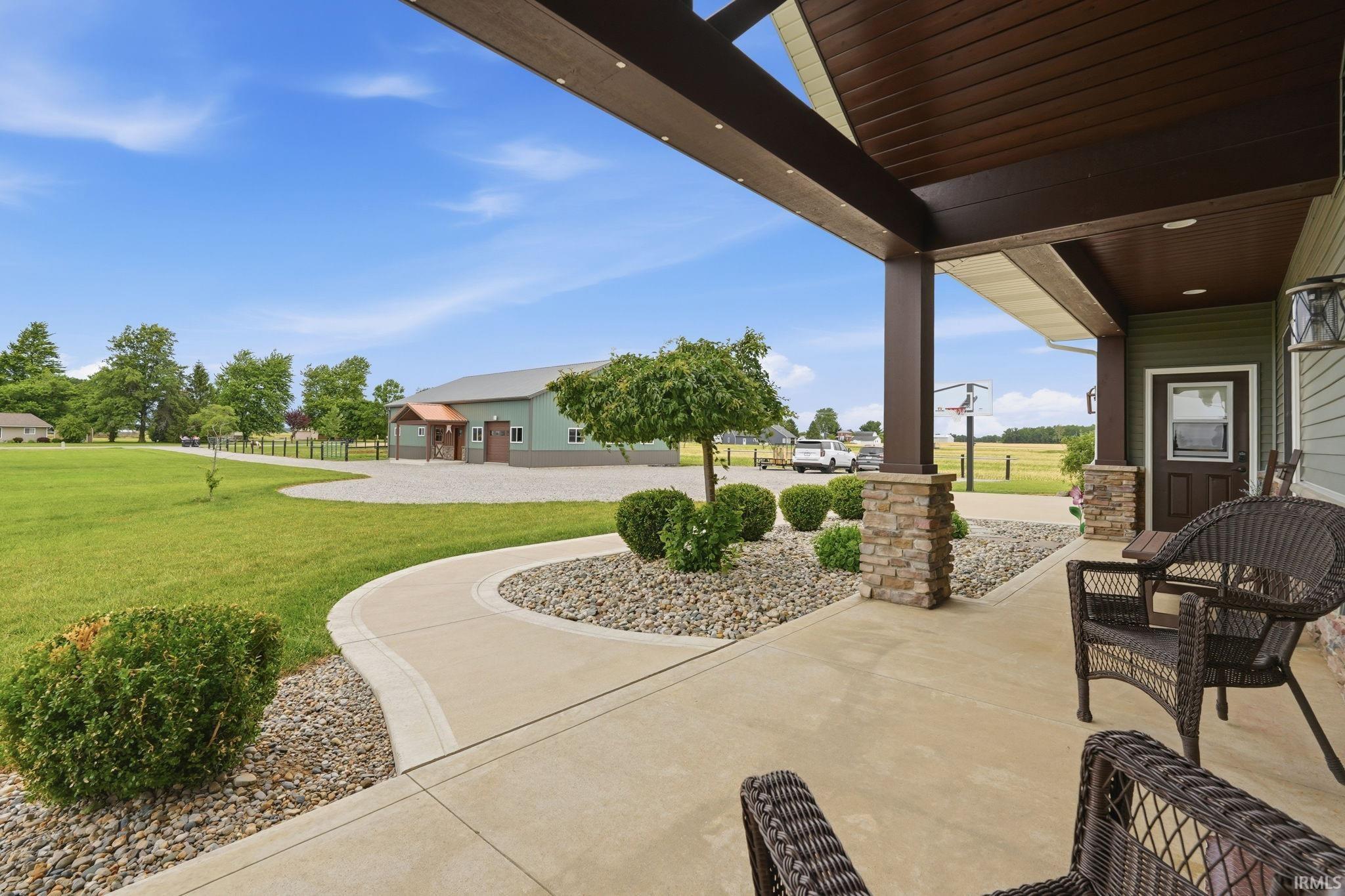 Covered porch featuring stone column bases, wood-finish ceiling, and a concrete patio