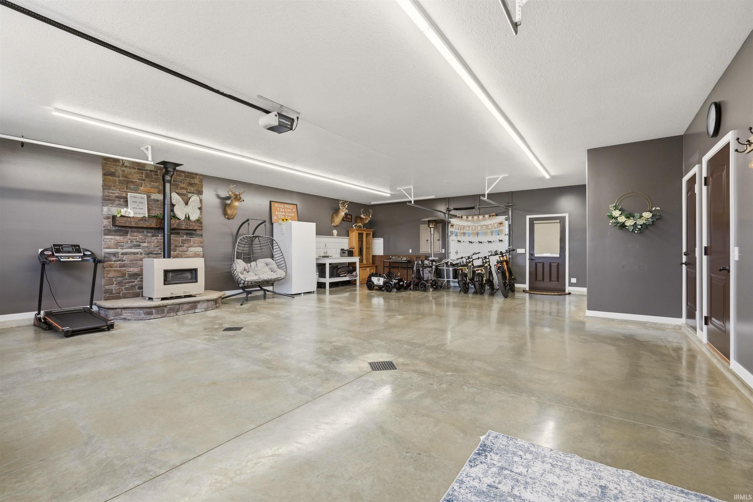 Spacious garage featuring a prominent stone-clad fireplace and hearth for separate family gatherings