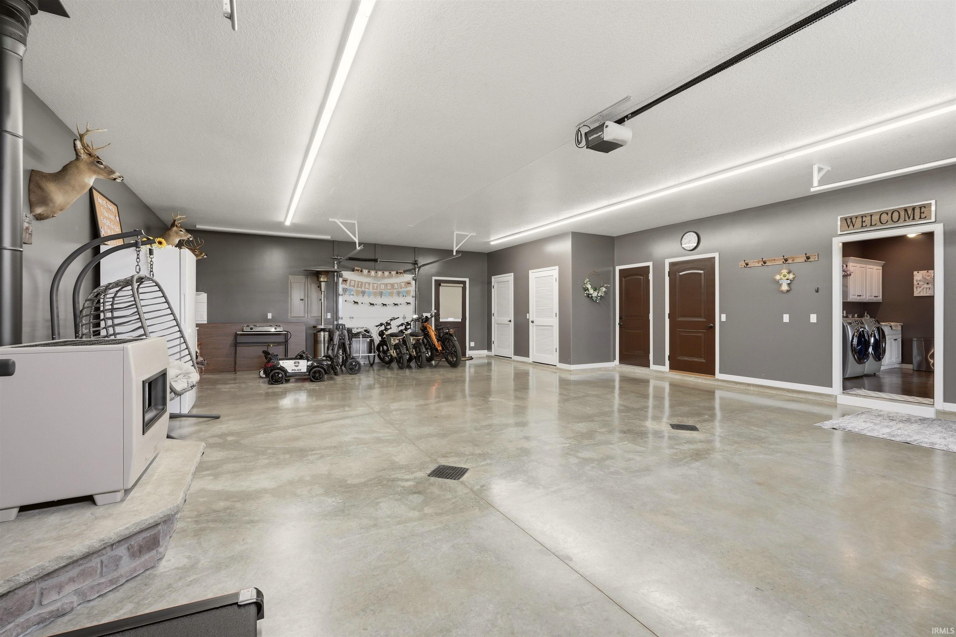 Spacious garage with polished concrete flooring, multiple access doors, high ceilings, and extensive linear lighting