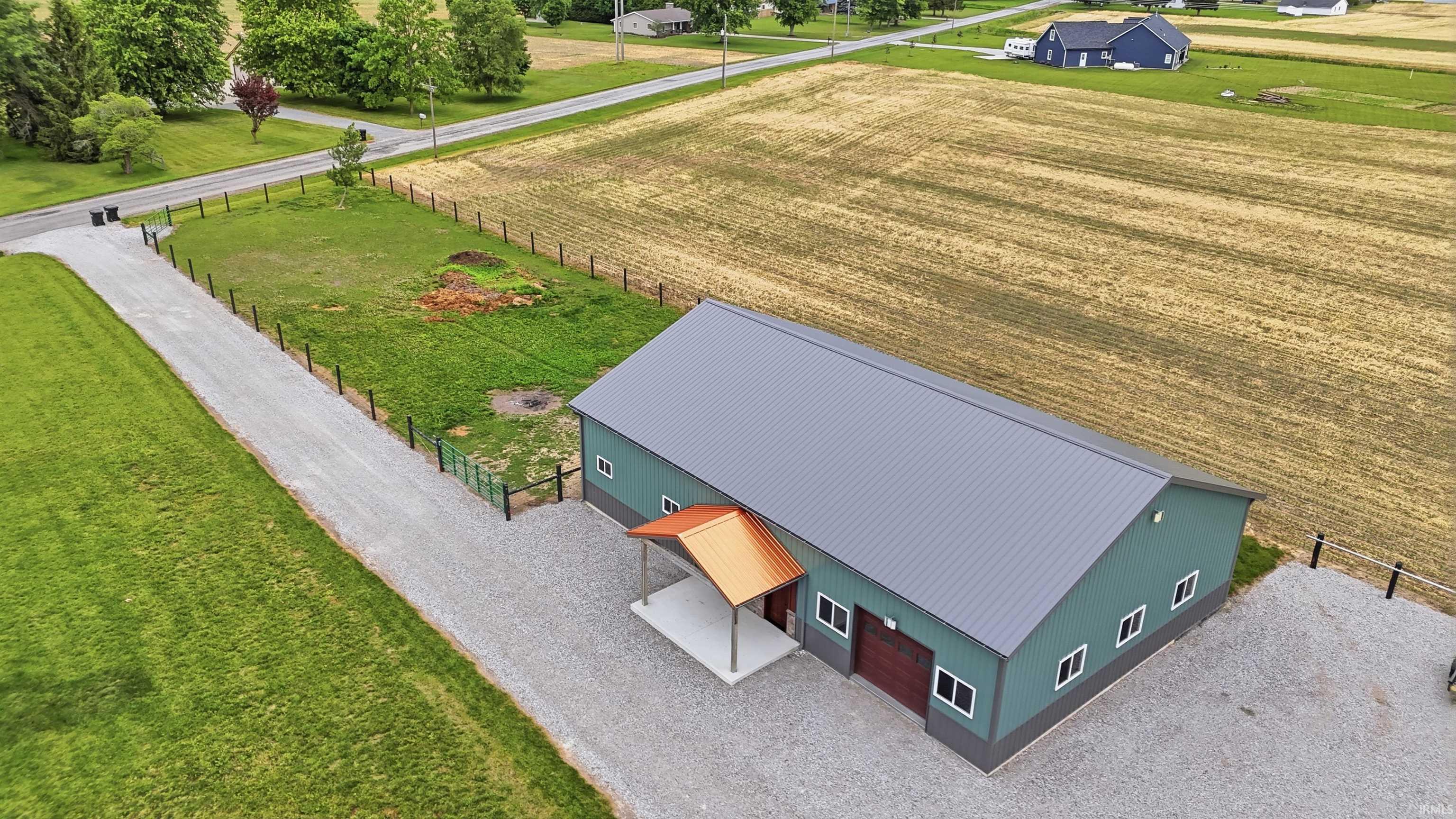 Metal-sided outbuilding featuring a gray metal roof and an orange metal awning over a concrete porch