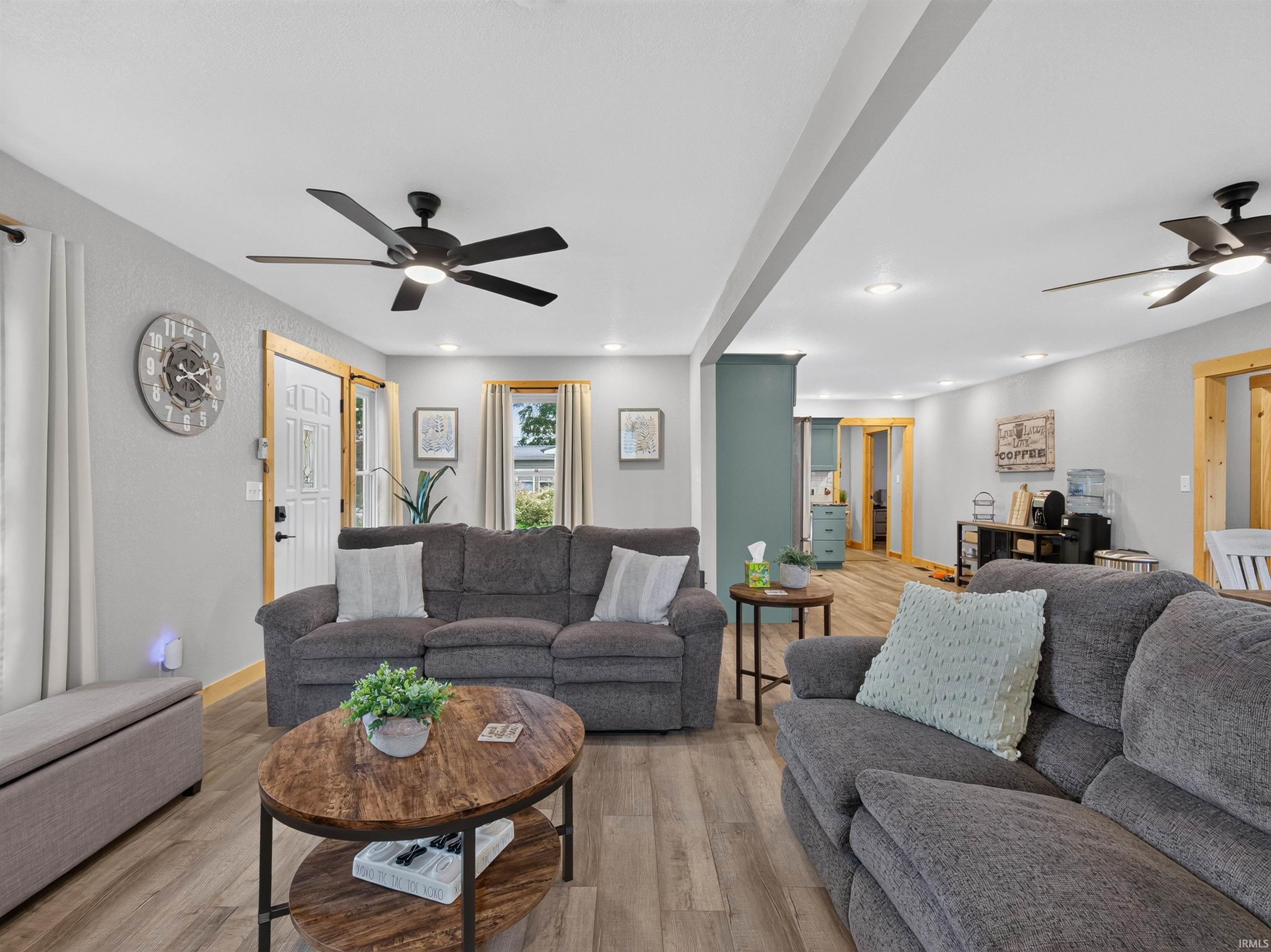 Spacious living area featuring light wood-finish flooring, recessed lighting, and ceiling fans