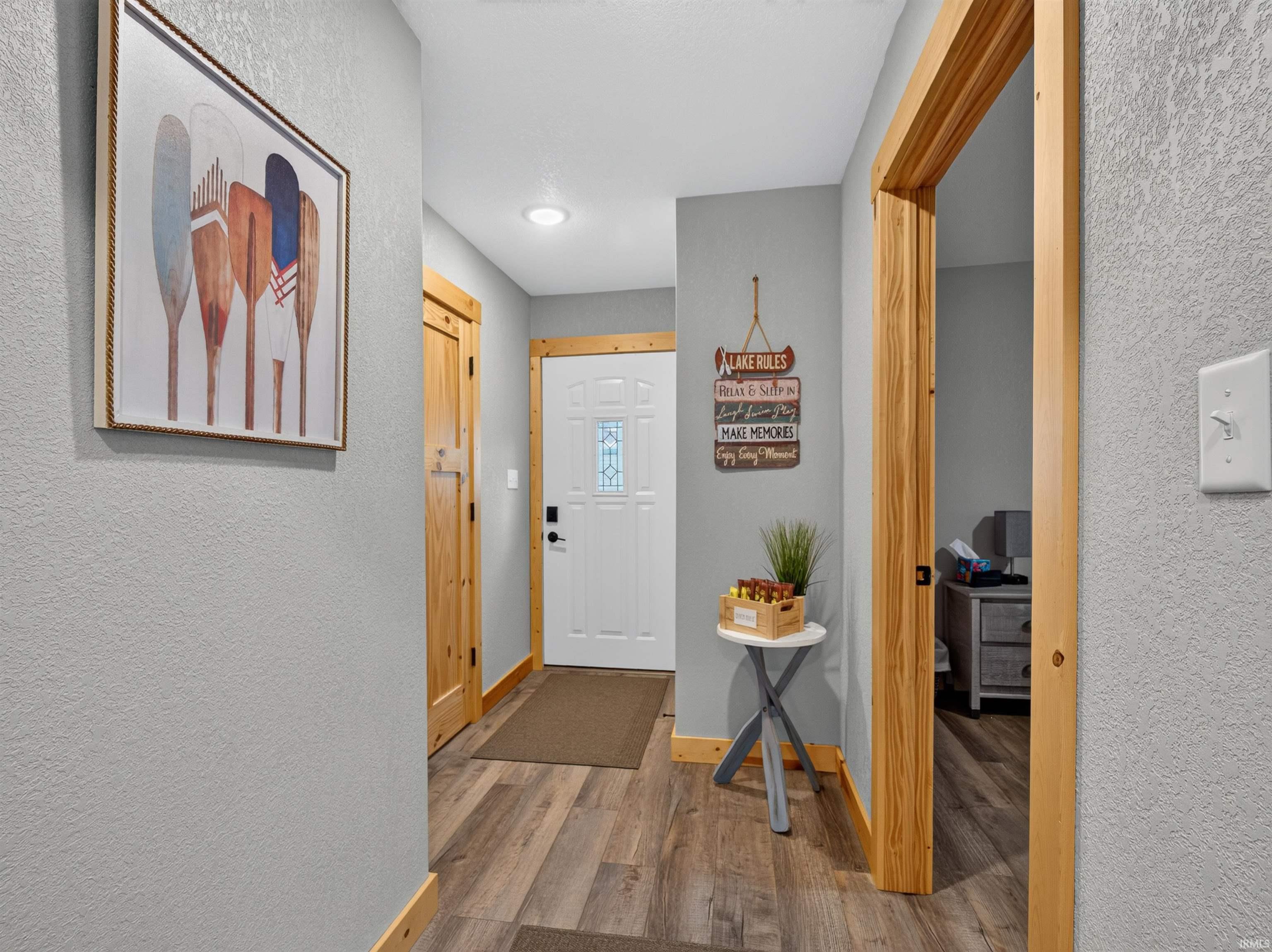 Inviting entryway featuring wood-finish flooring, light gray walls, and natural wood trim throughout