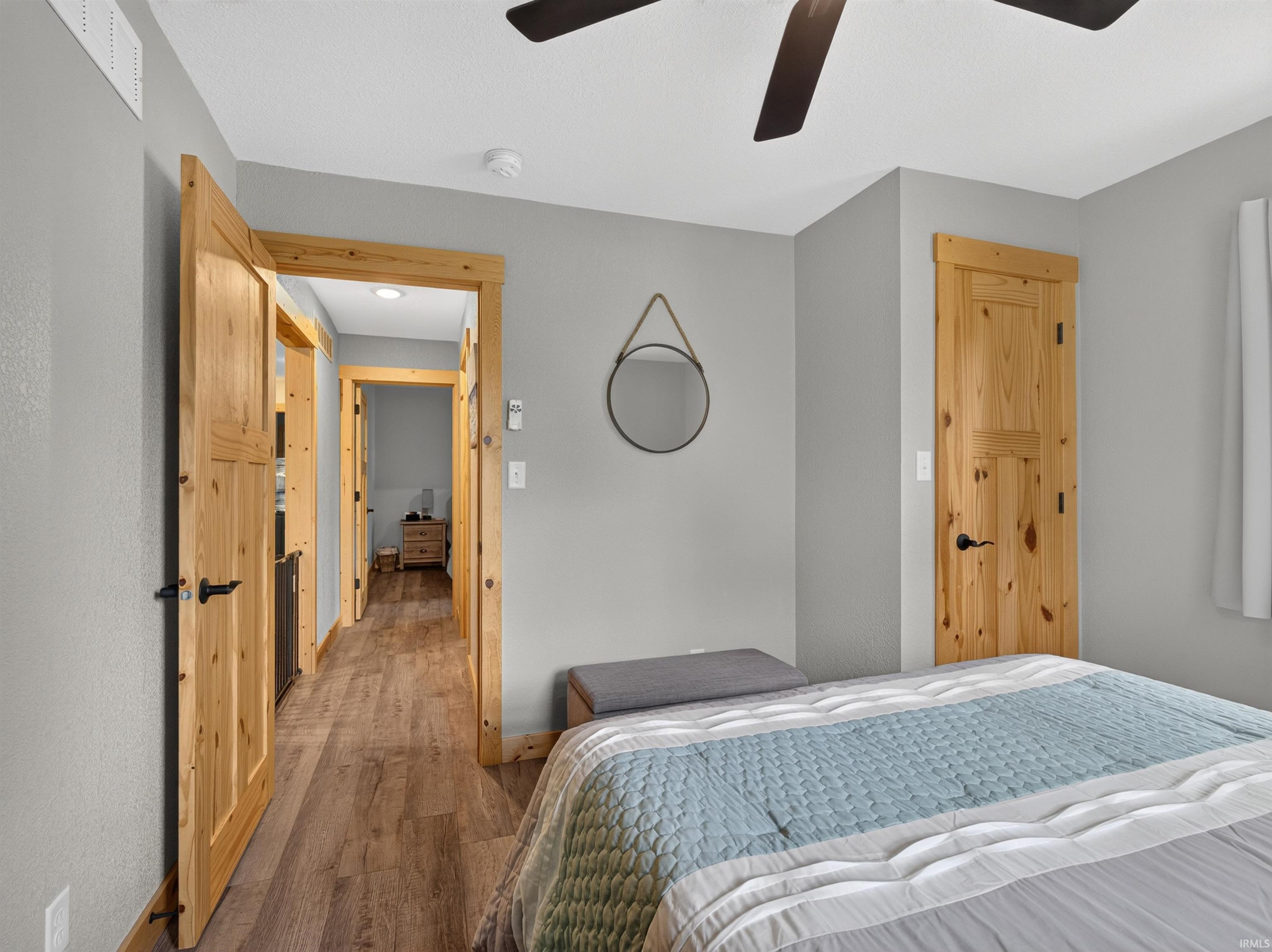 Bedroom featuring a dark-toned ceiling fan, solid wood doors with black hardware, and wood-finish flooring