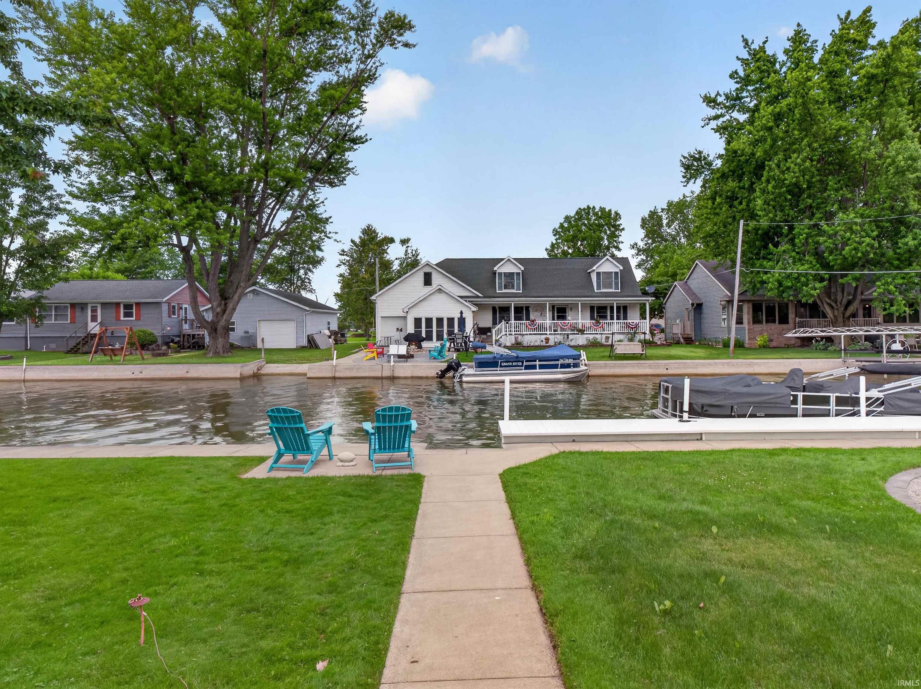 Waterfront property featuring a private boat dock, manicured lawn, and mature trees