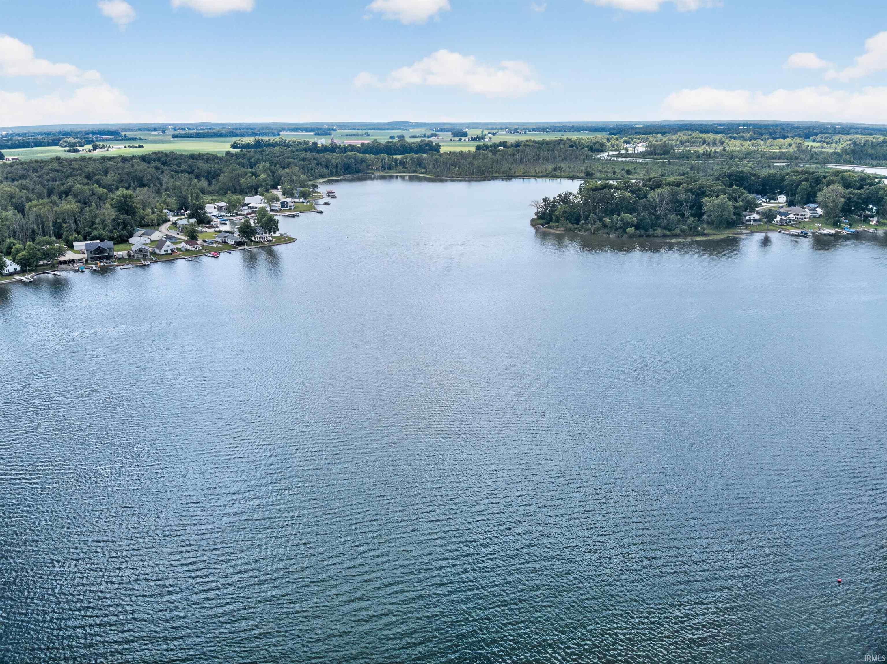 Expansive lake with a clear shoreline, surrounded by mature trees and residential properties