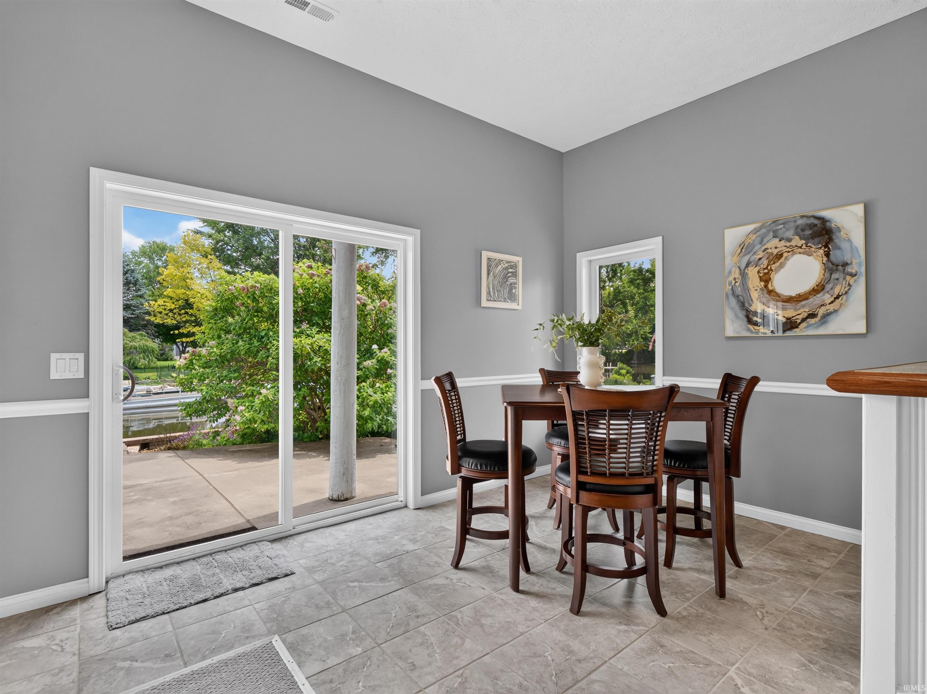 Dining area featuring tile flooring, a chair rail, and a vaulted ceiling