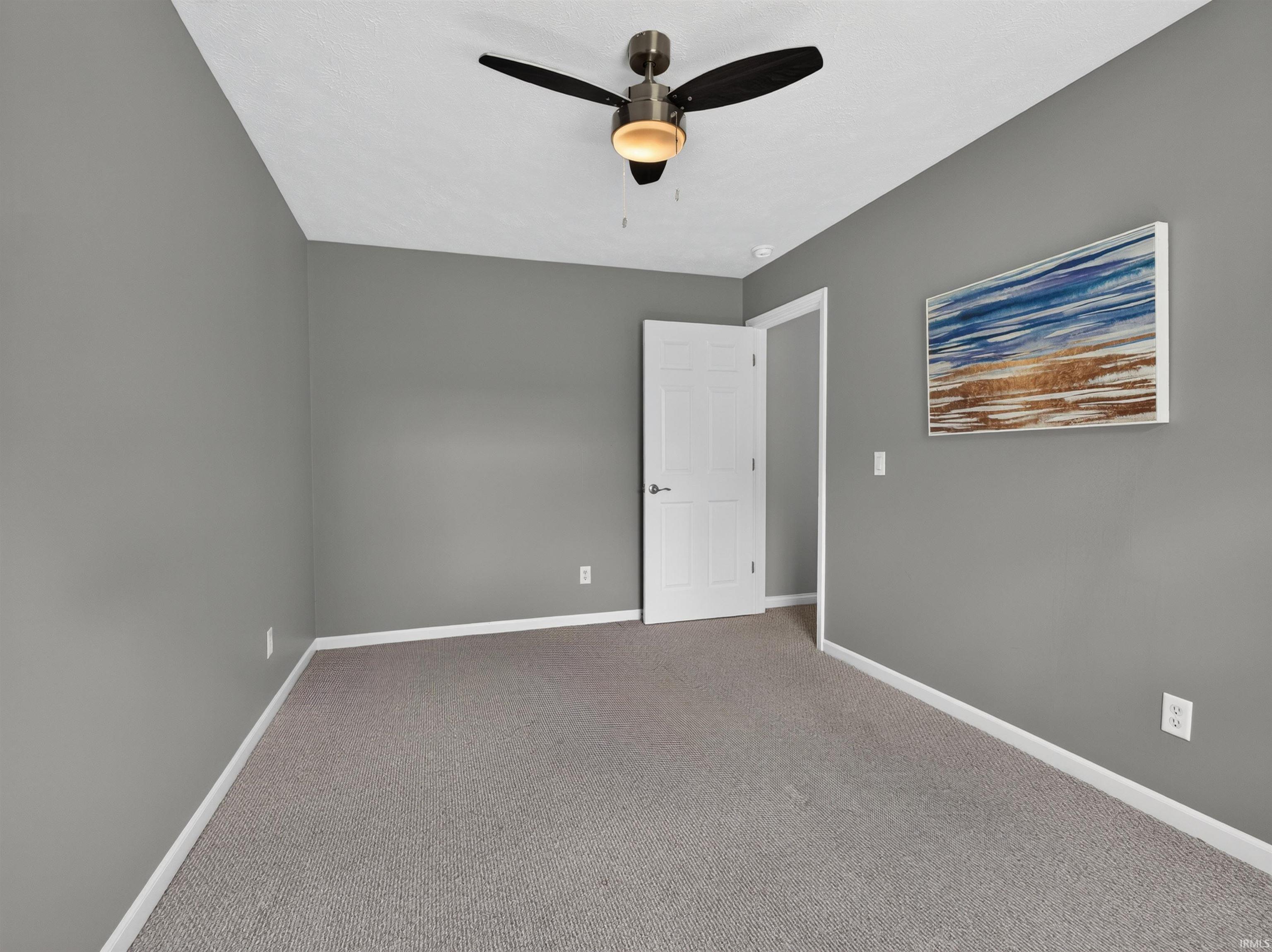Carpeted room featuring gray walls, white trim, and a ceiling fan with integrated lighting