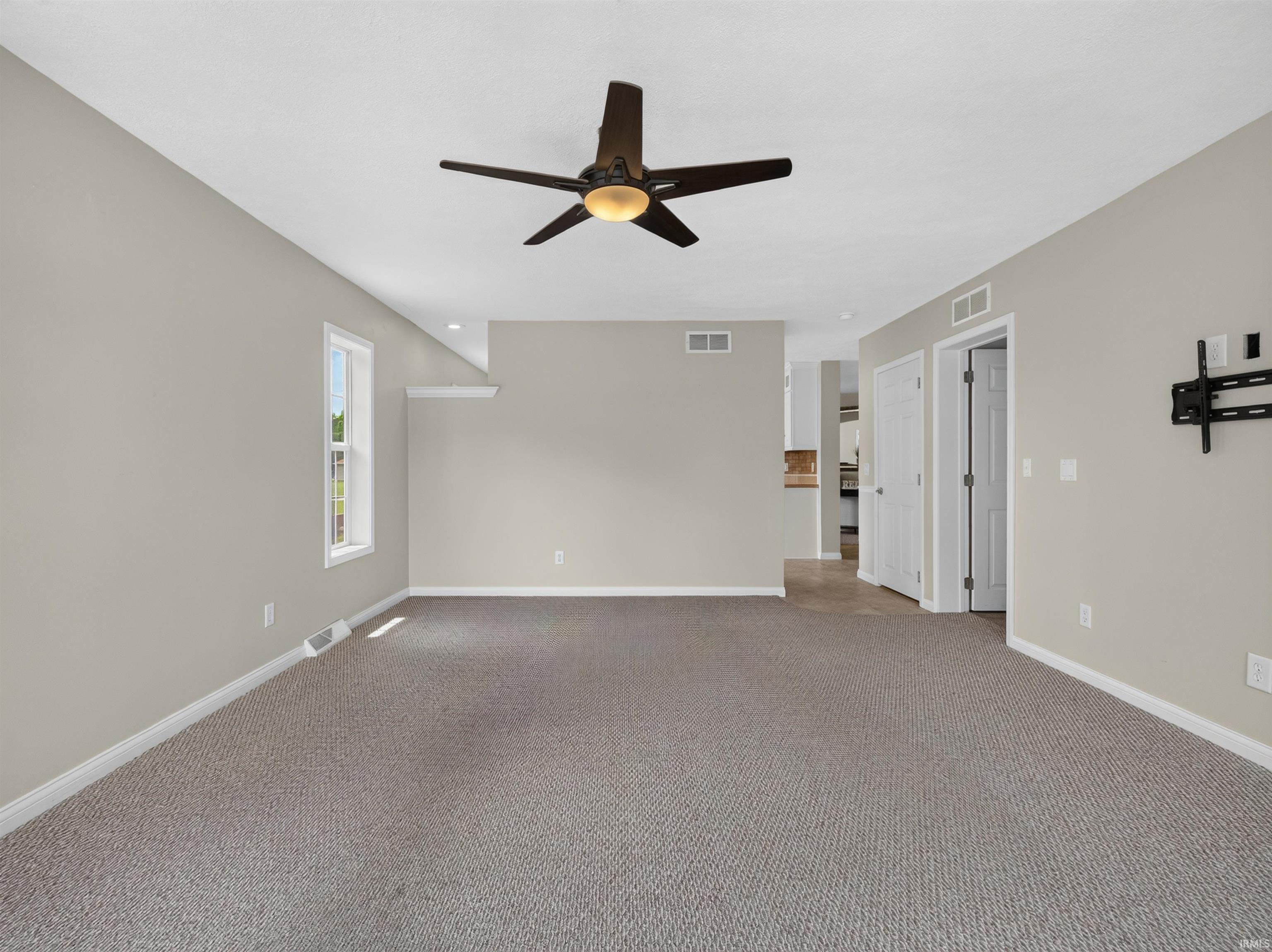 Spacious room with neutral gray walls, light gray carpet, and white trim