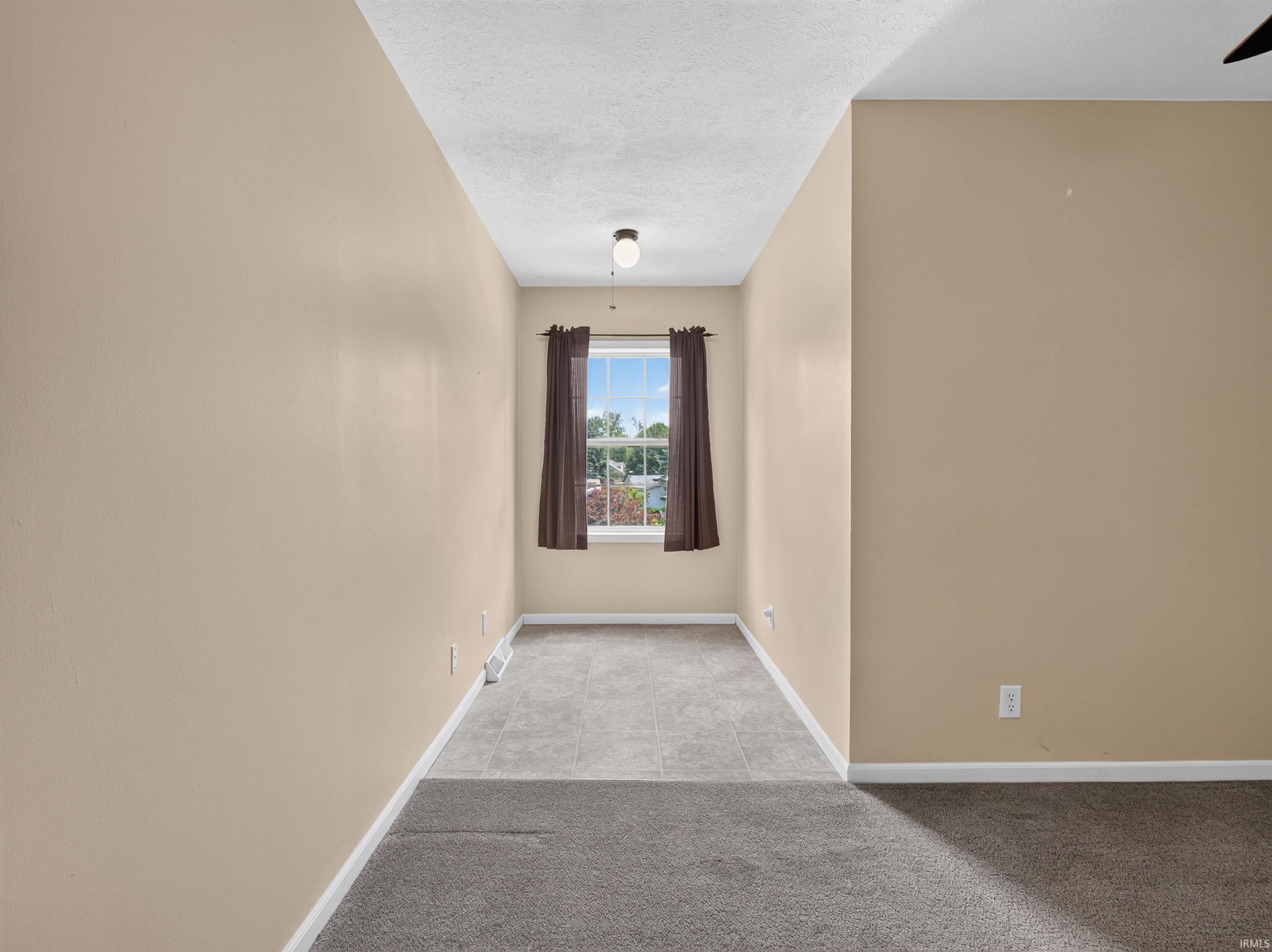 Neutral-toned room with a window providing natural illumination, complemented by an overhead light fixture