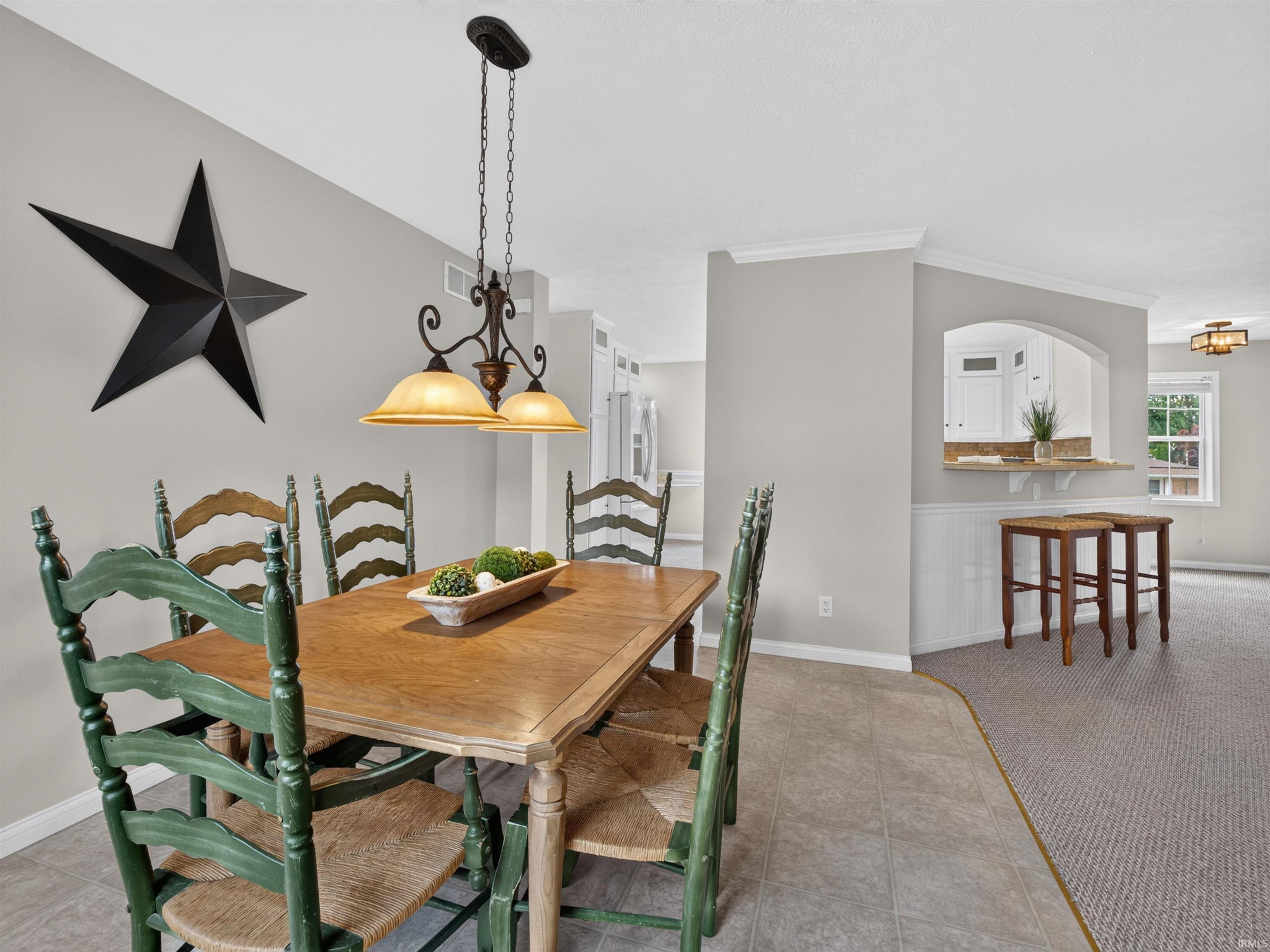 Dining area featuring a decorative pendant light fixture, tile flooring, and a pass-through window with a stone countertop