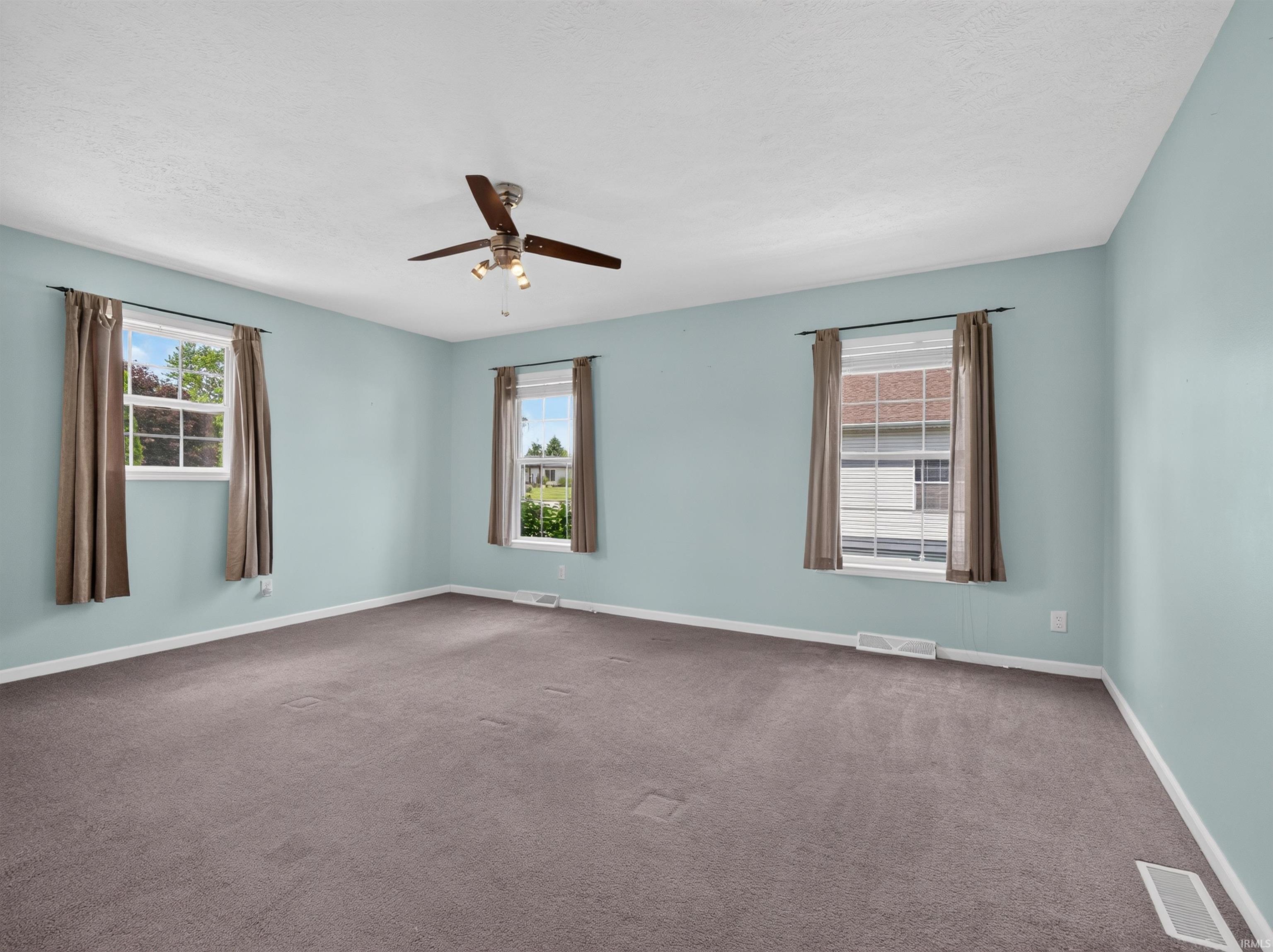 Spacious room featuring light blue walls, gray carpet, and a white ceiling