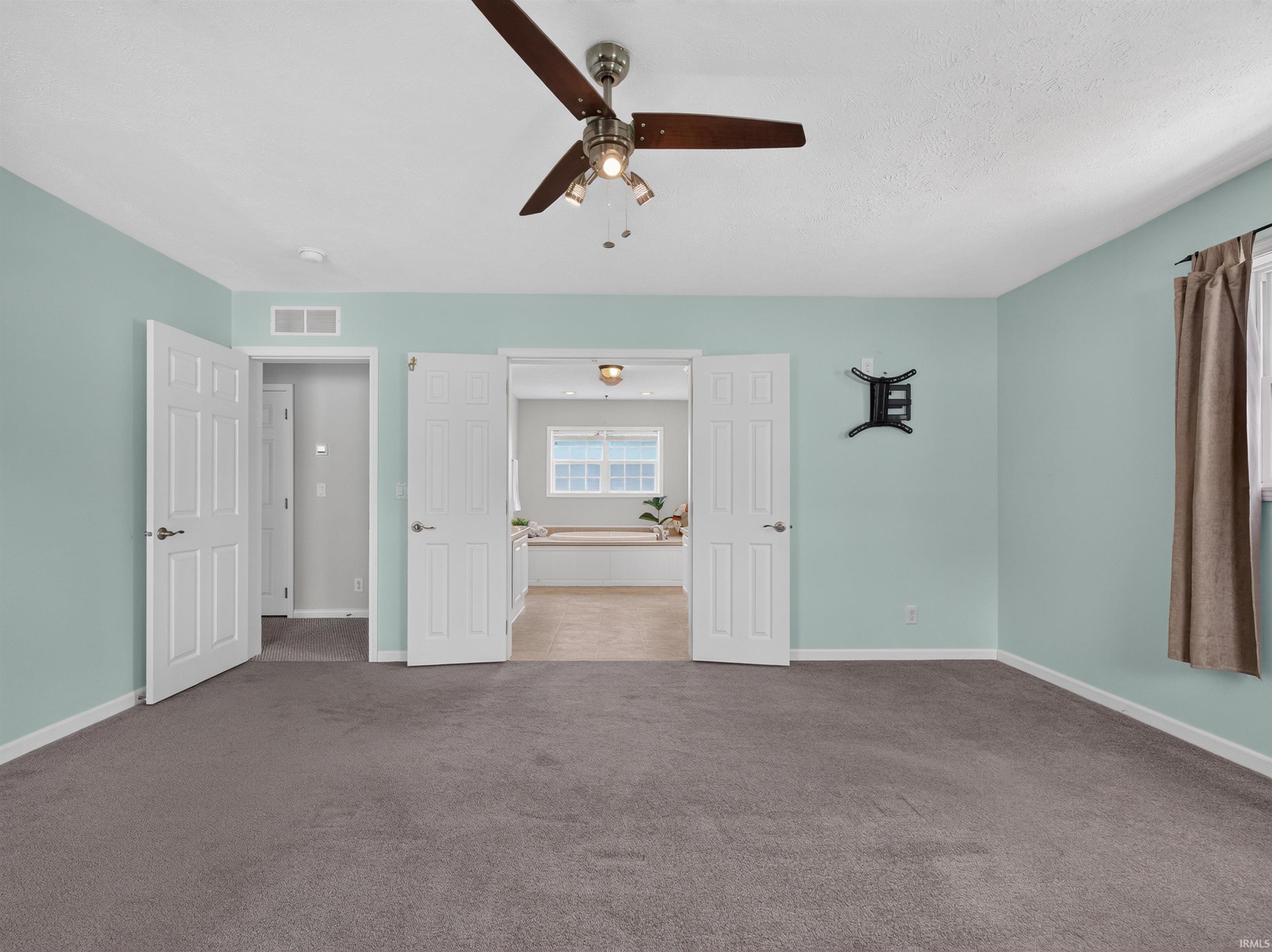 Spacious room featuring neutral carpeting and light blue painted walls