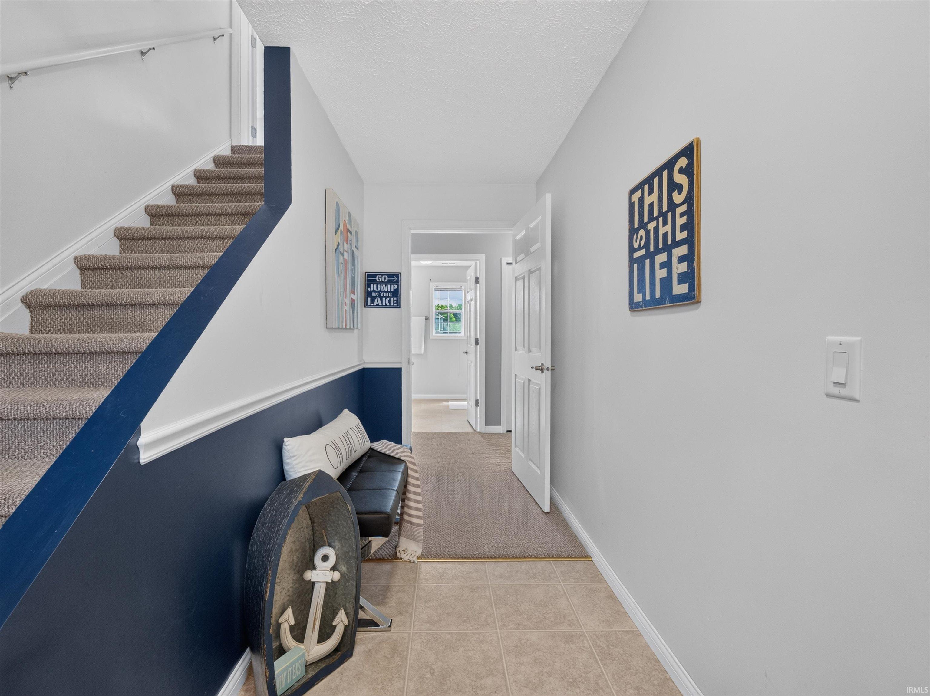 Entryway featuring a carpeted staircase with white handrails and a two-tone wall treatment