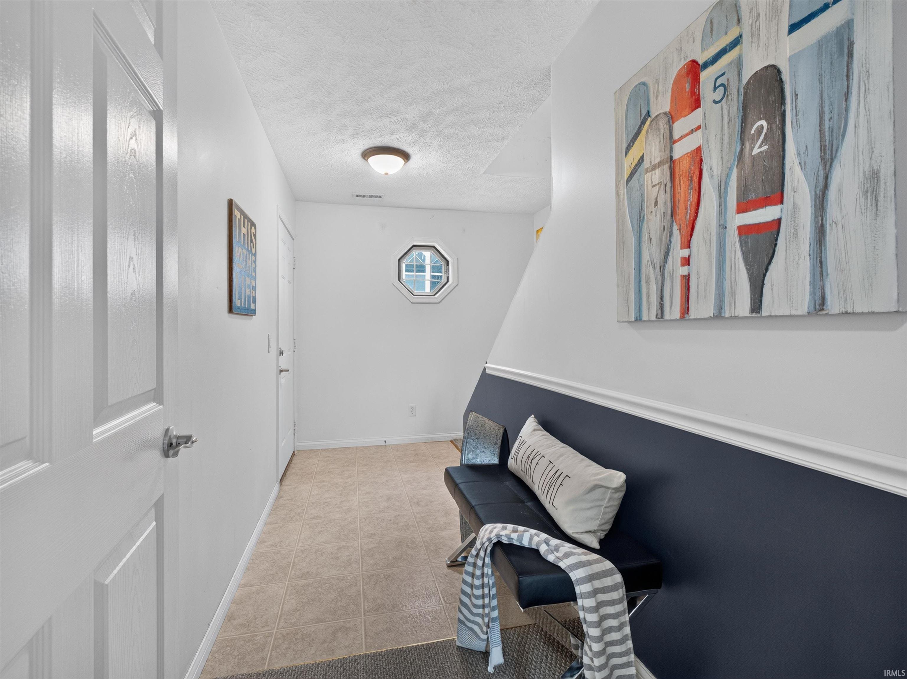 Entryway featuring ceramic tile flooring, a half-wall with chair rail molding, and an octagonal window