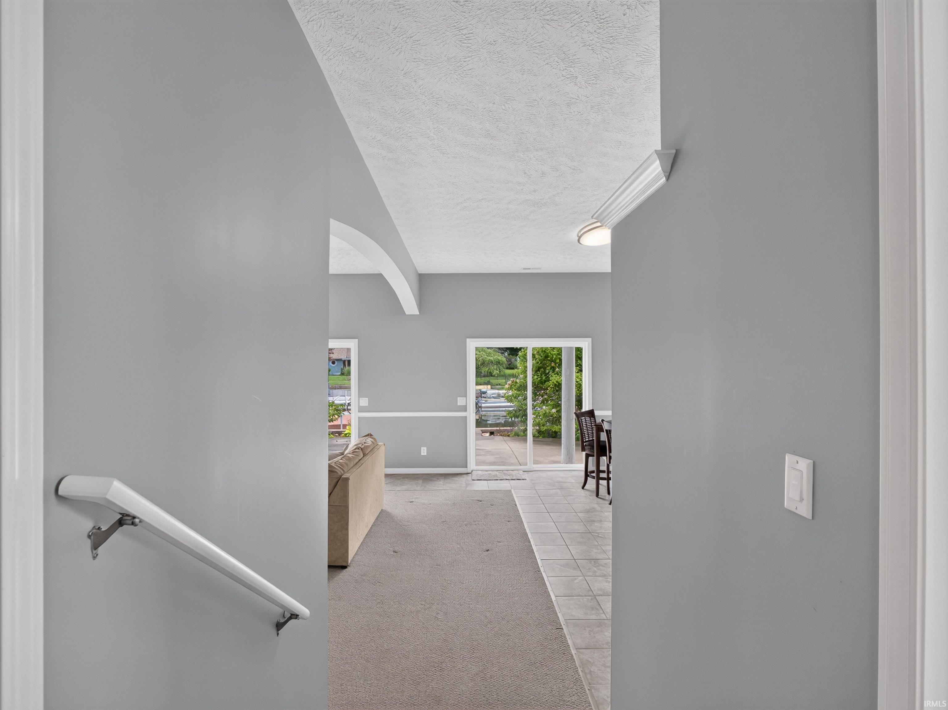 Open-concept interior featuring light gray wall paint, vaulted ceilings, and crown molding accents