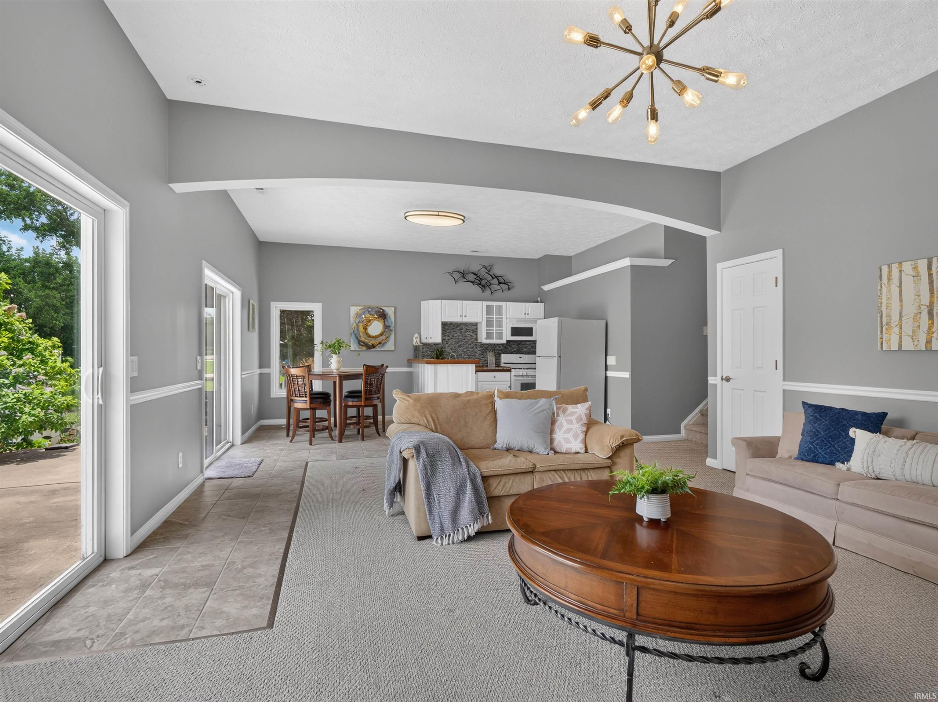 Spacious living area featuring a vaulted ceiling and contemporary light fixtures