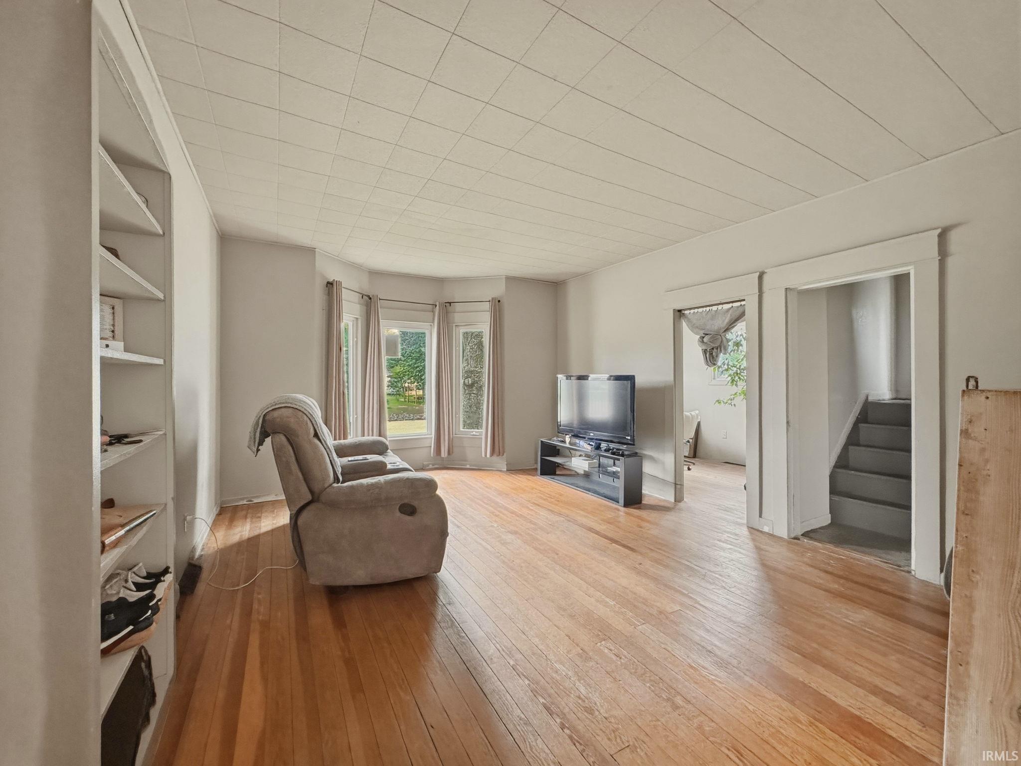 Expansive living area featuring wood-finish flooring, built-in shelving, and a bay window