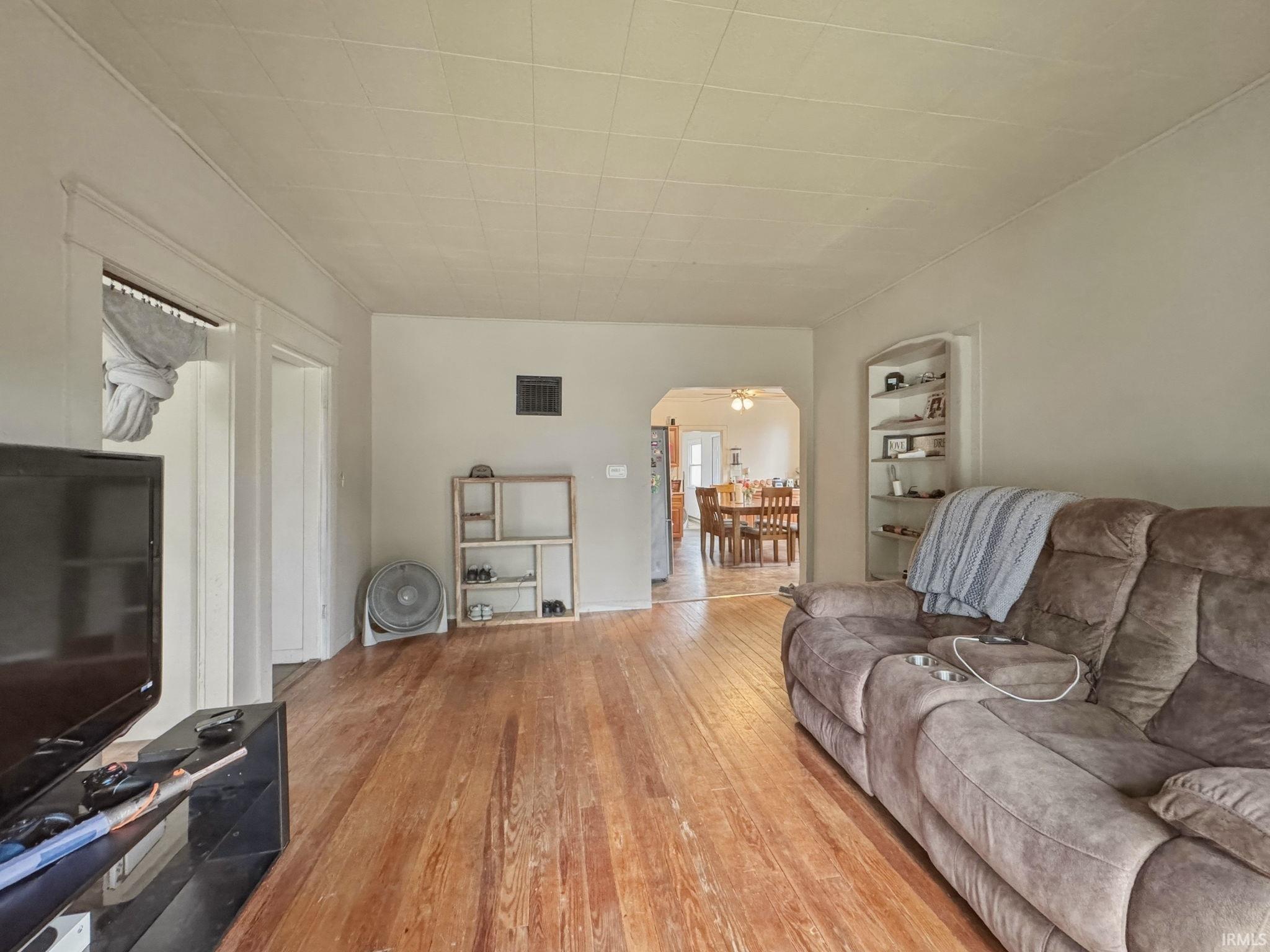 Living area featuring warm wood flooring, neutral wall tones, and recessed built-in shelving