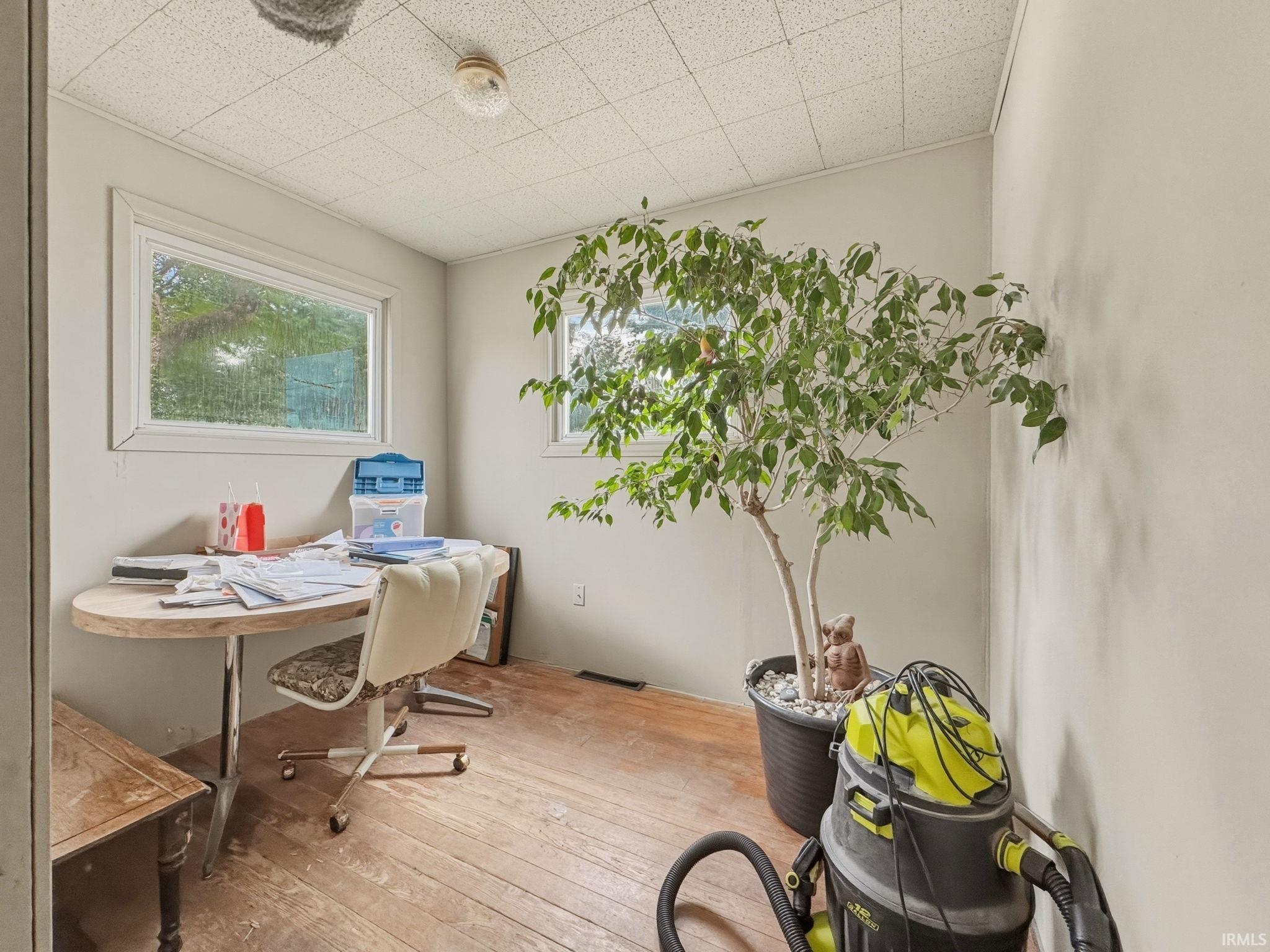 Room featuring hardwood flooring, light-toned walls, and multiple windows