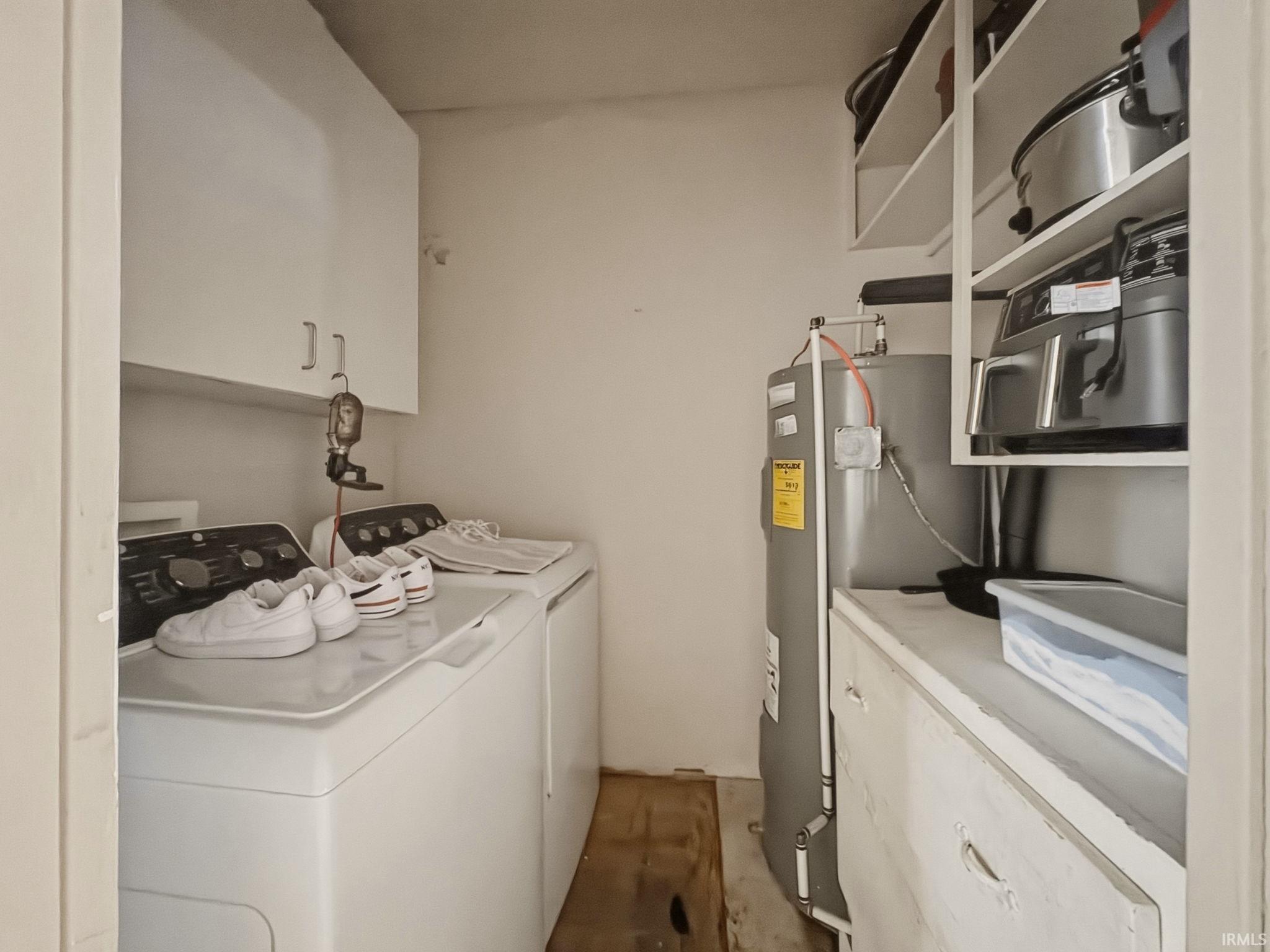 Laundry area featuring a top-load washing machine, a front-load dryer, and overhead cabinetry