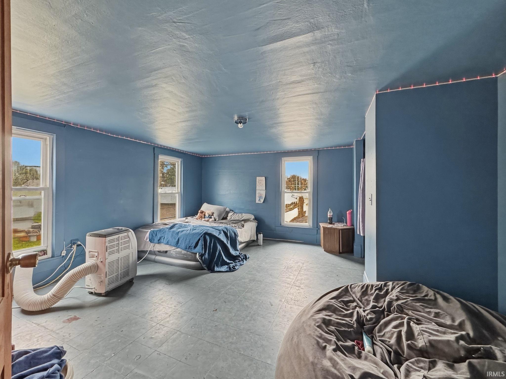 Room featuring a light blue painted ceiling and walls, two double-hung windows, and light-colored flooring