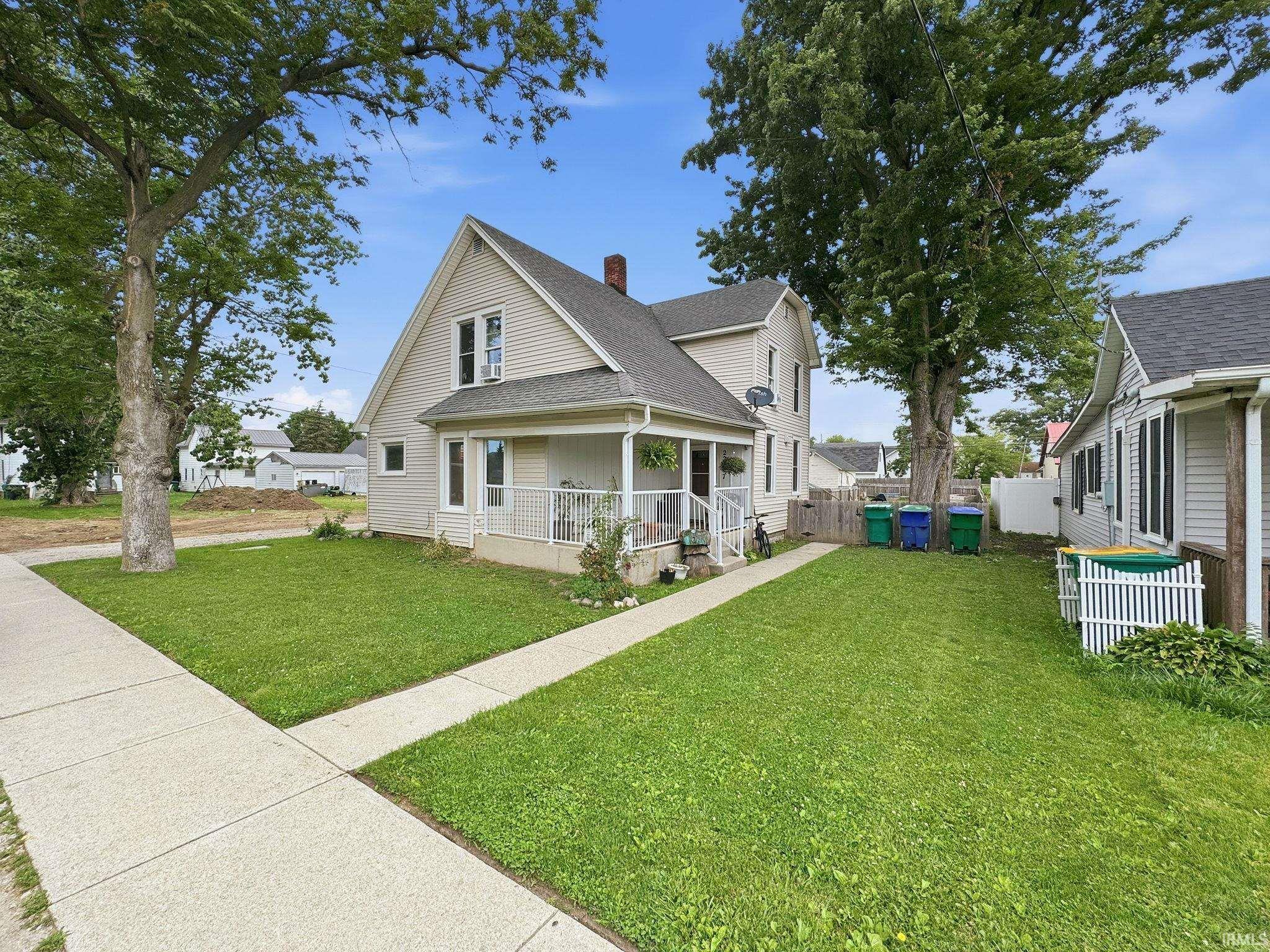 Two-story residence featuring light-colored siding and a covered front porch with white railing