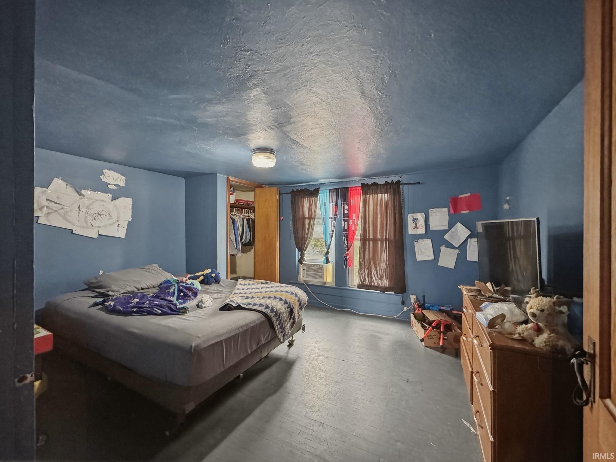 Room featuring painted blue walls and ceiling with a textured finish, a built-in closet with bifold doors, and two windows