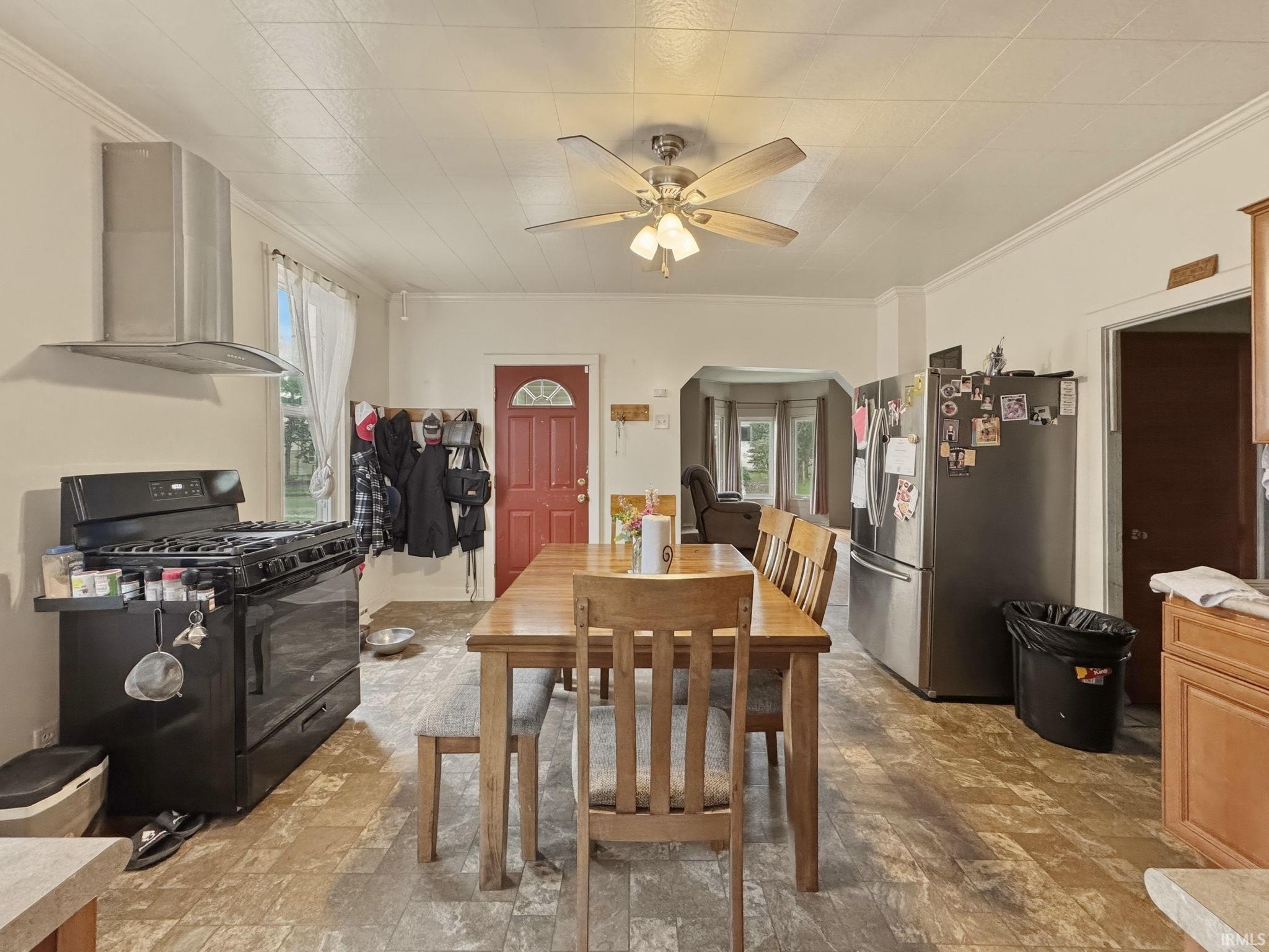 Eat-in kitchen featuring wood-finish flooring, a stainless steel range hood, and a red entry door