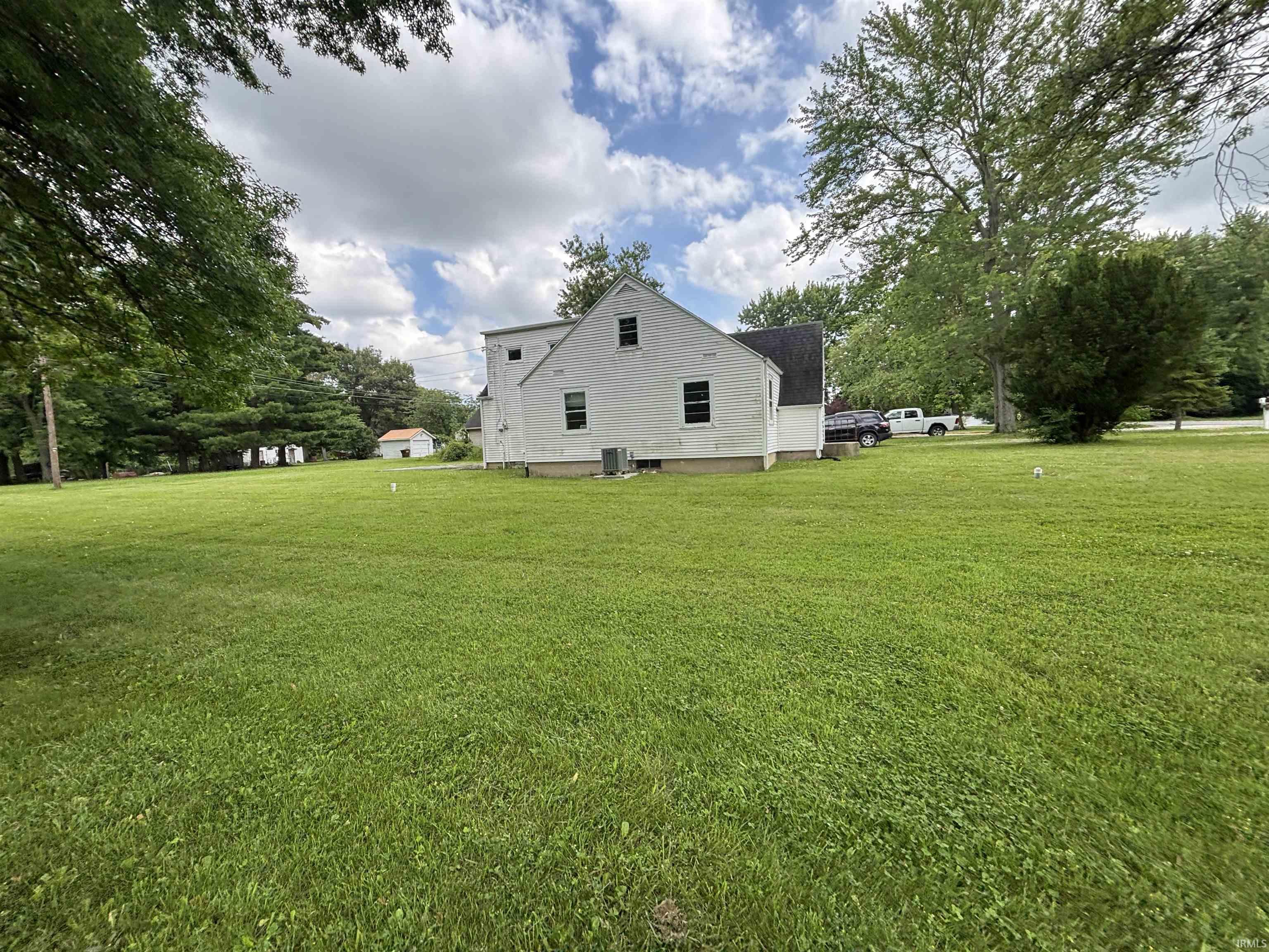 Expansive green lawn surrounds the white-sided residence with dark-shingled roofing