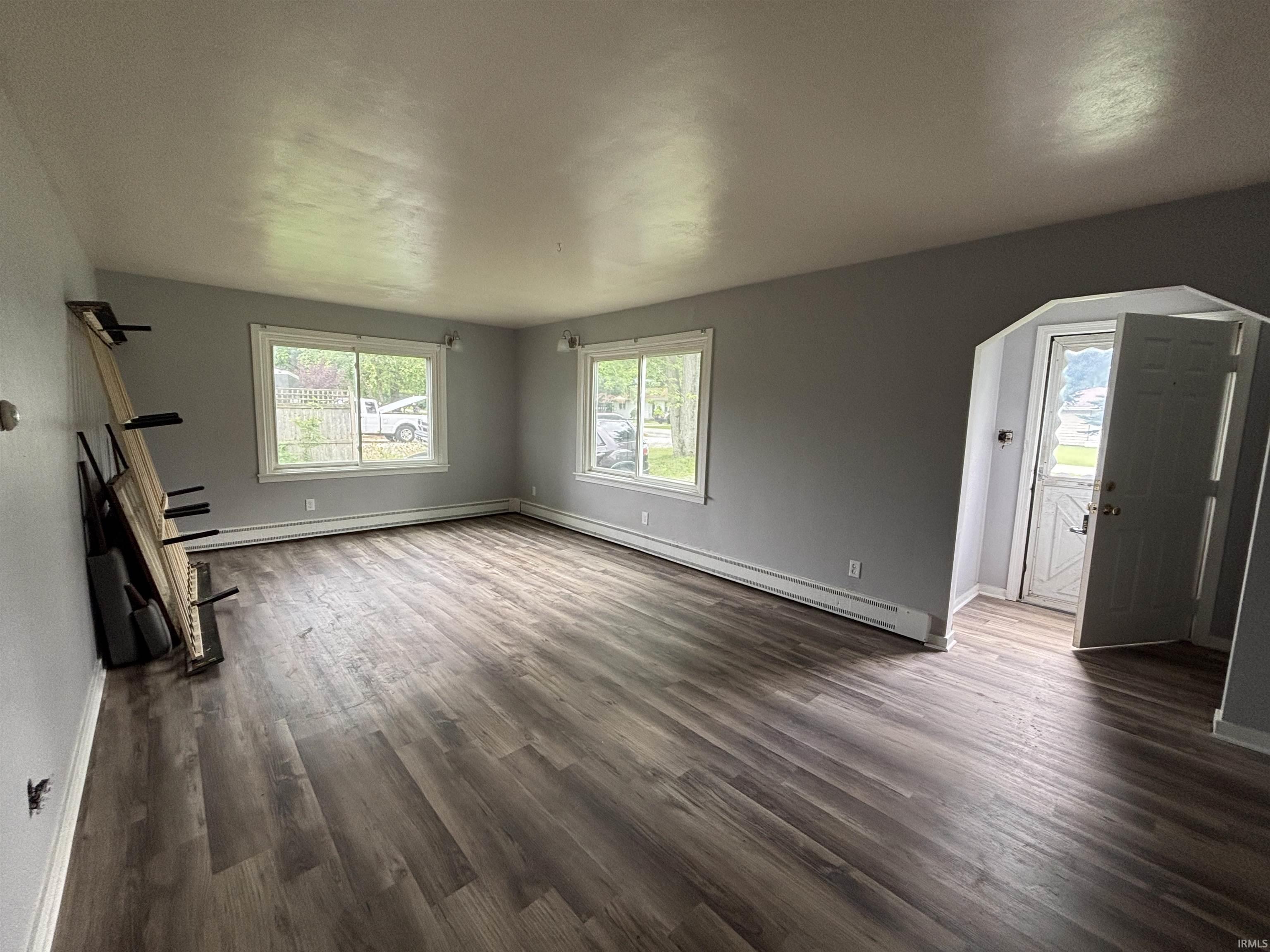 Expansive room featuring wood-finish flooring, light gray walls, and multiple large windows with white trim