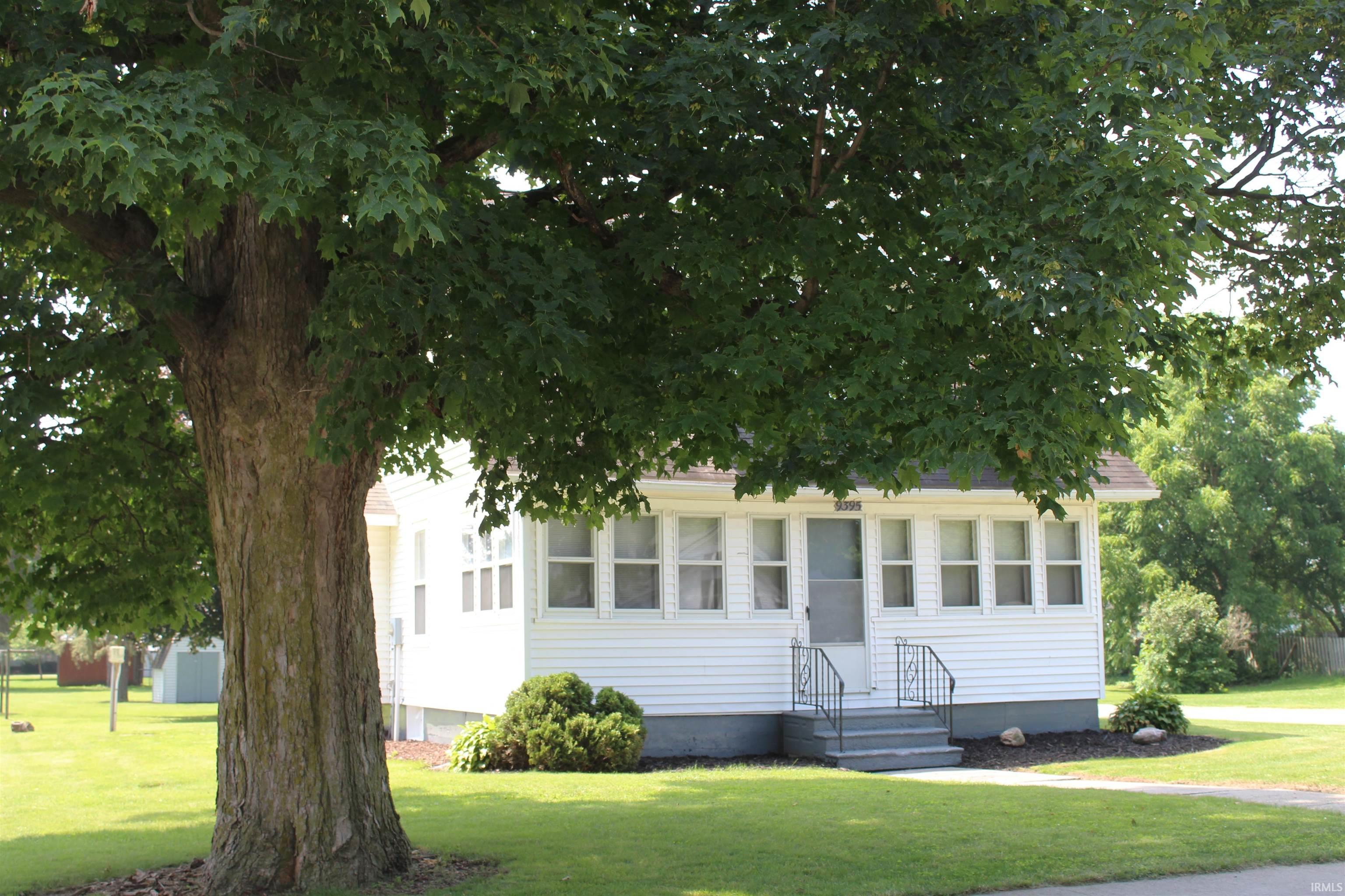 White siding residence featuring multiple front windows, a grey entry staircase with black handrails, and a dark front door