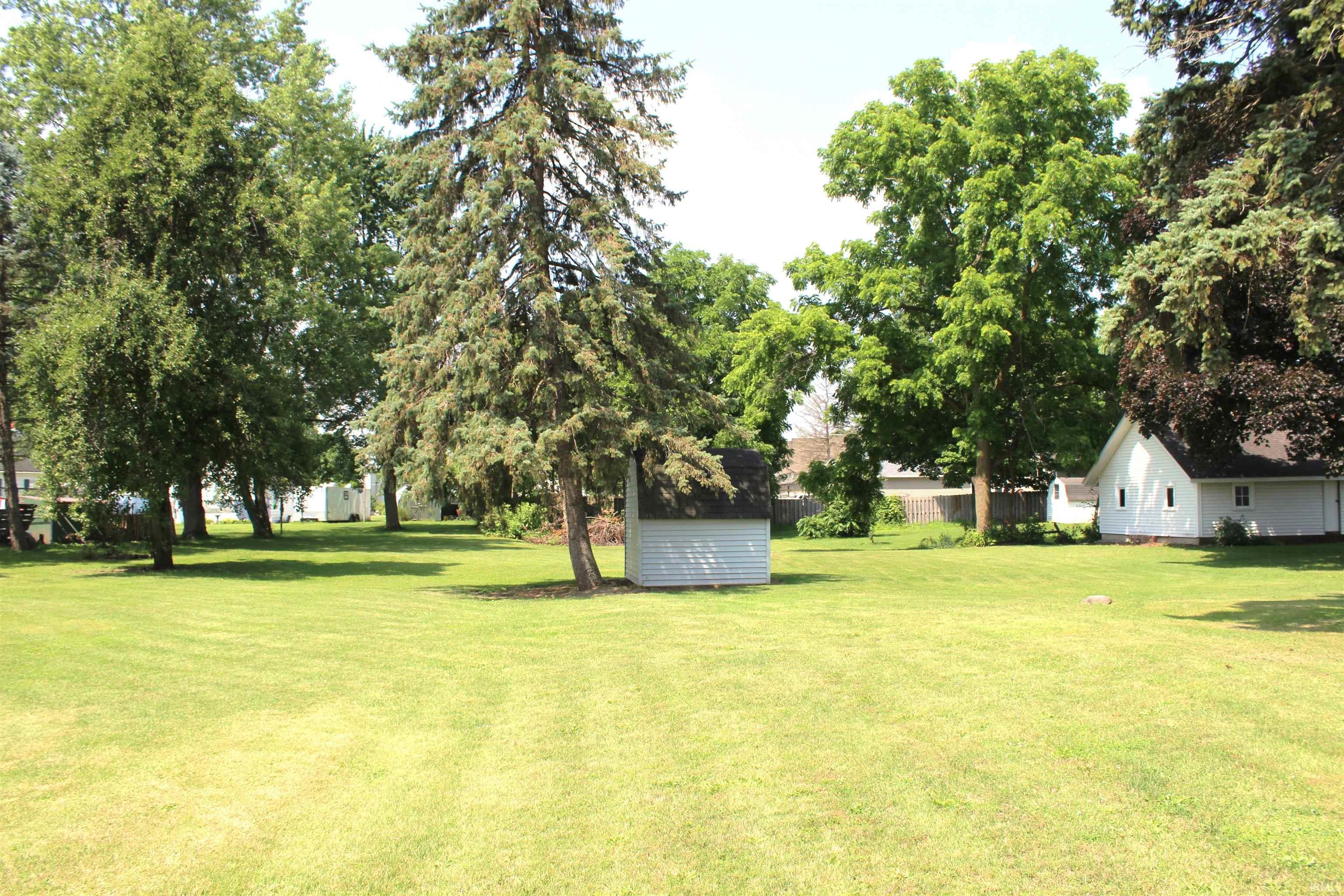 Expansive green lawn with mature trees providing shade