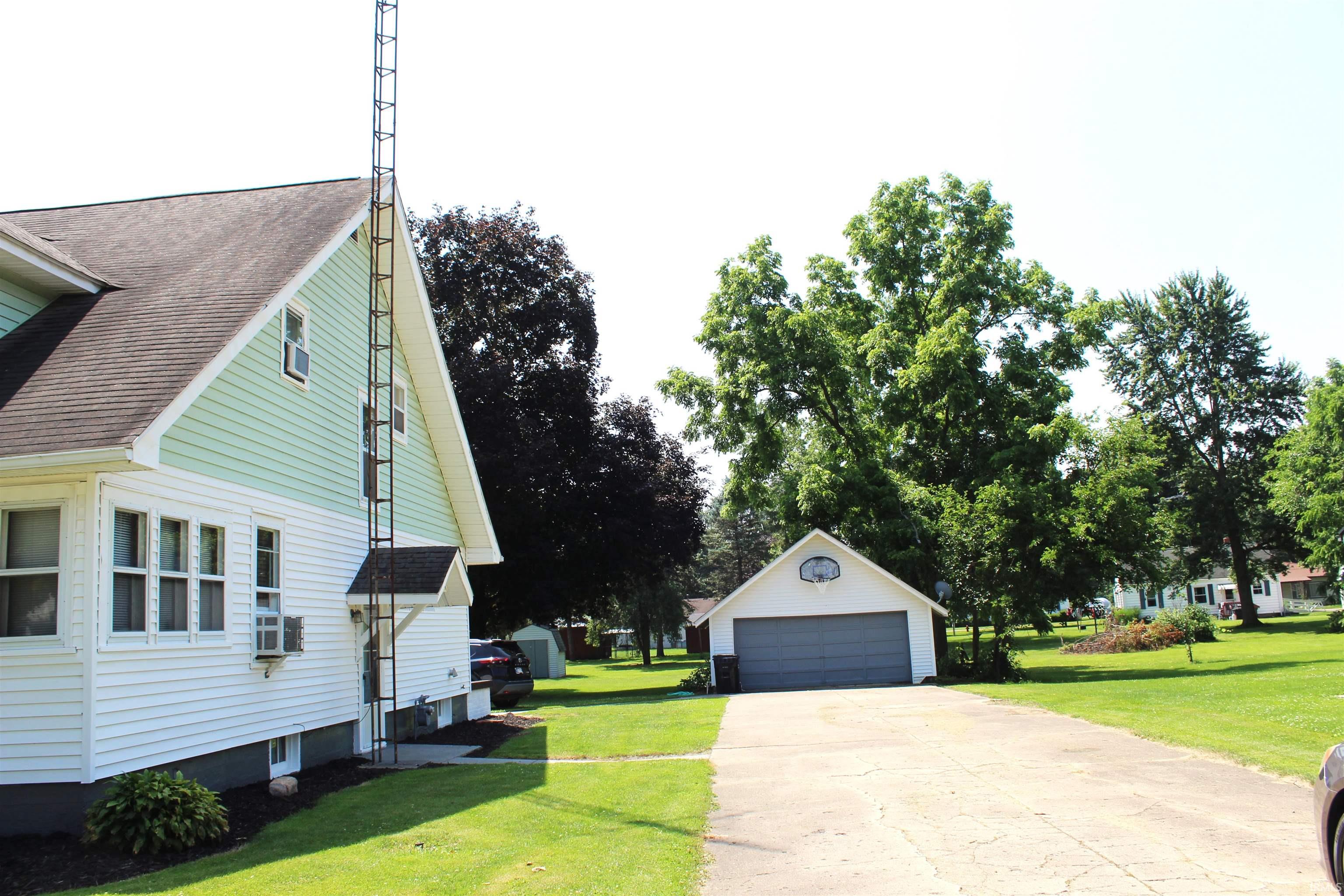 Detached garage with a gray overhead door, accompanied by a paved driveway and a verdant lawn